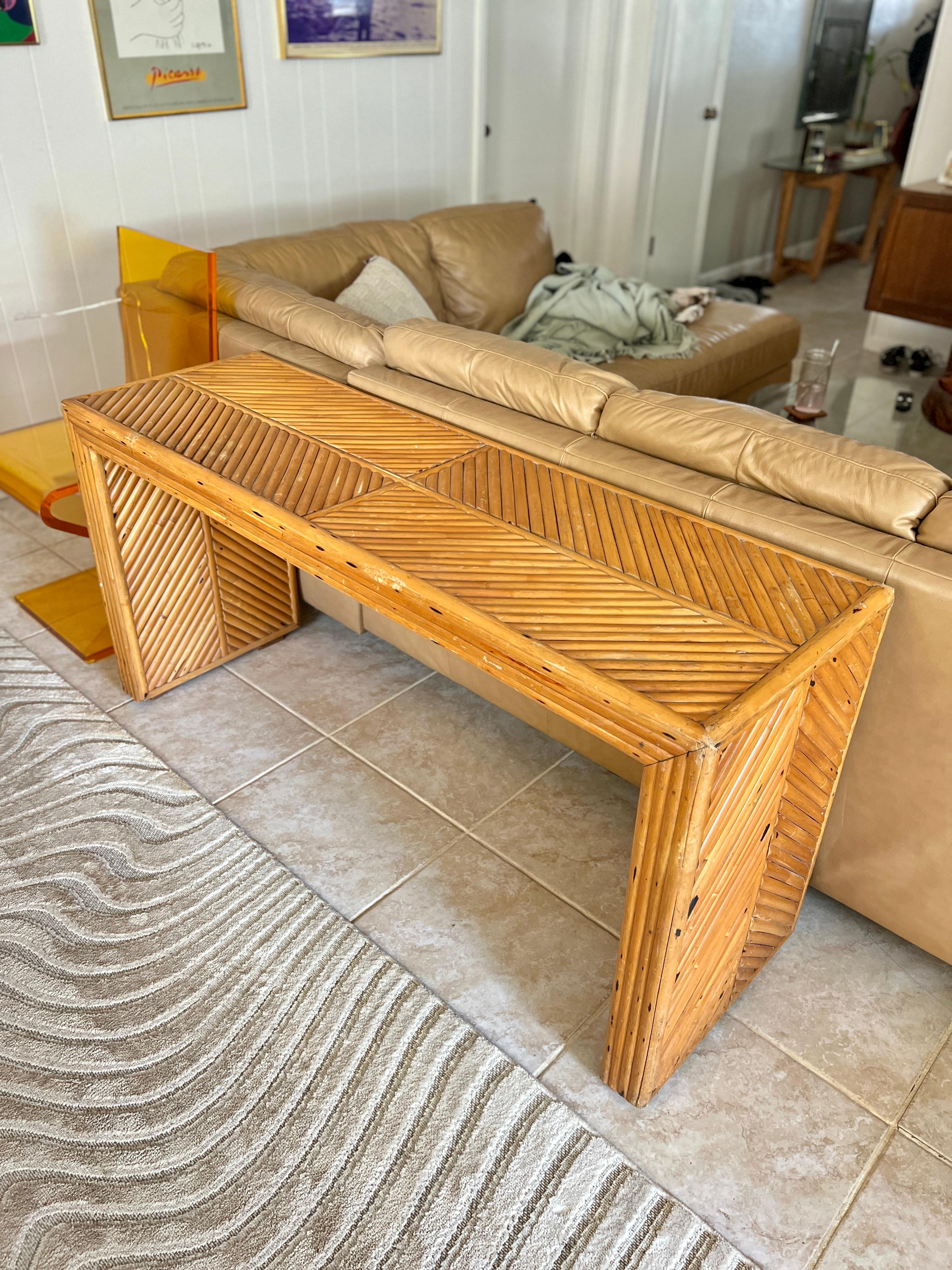 Vintage rattan sharp edged waterfall console table. With a beautiful chevron pattern on its top and sides. Circa 1970s. Can also be used as a desk. It is in good vintage condition with just one little bamboo missing on the inner right leg. Please