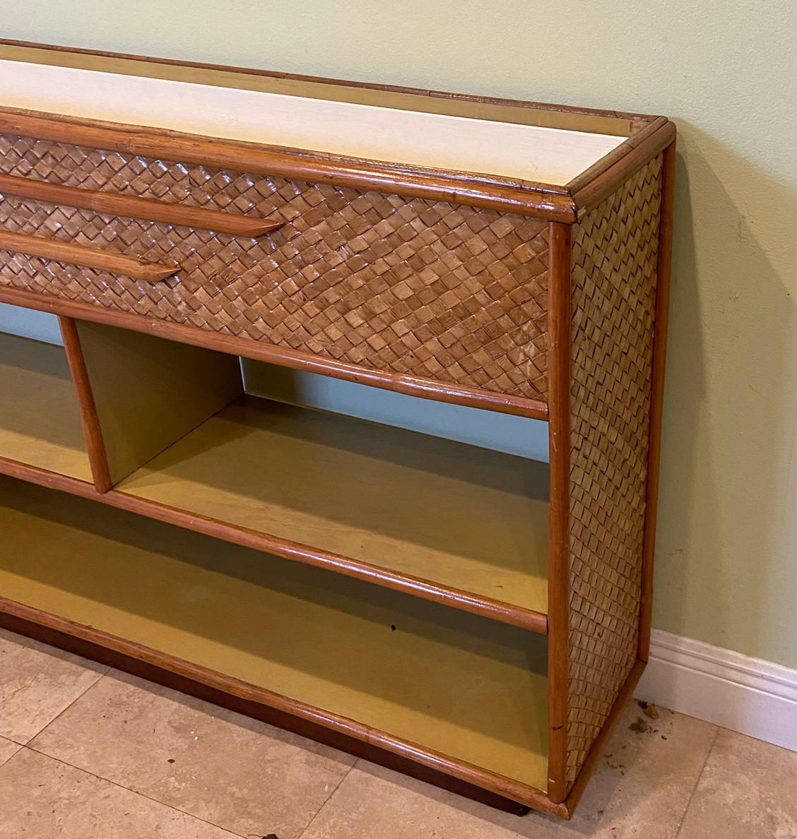 Vintage rattan shelving unit with a built in planter. Herringbone decoration on this very versable cabinet. Can be used in the kitchen to display China, in a sun room as an accent piece. The planter can be turned upside down to make it even with the