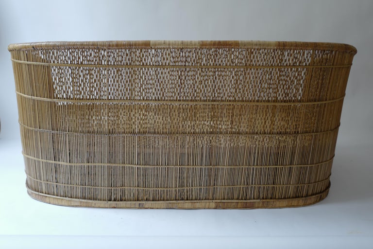 This two seat vintage rattan sofa was found in a villa in the South of France. The owner believed it to be Brasilian rattan. Beautiful woven design on seat. Truly one of a kind. Great for outdoors on a terrace or in a cabana. Comes as is without
