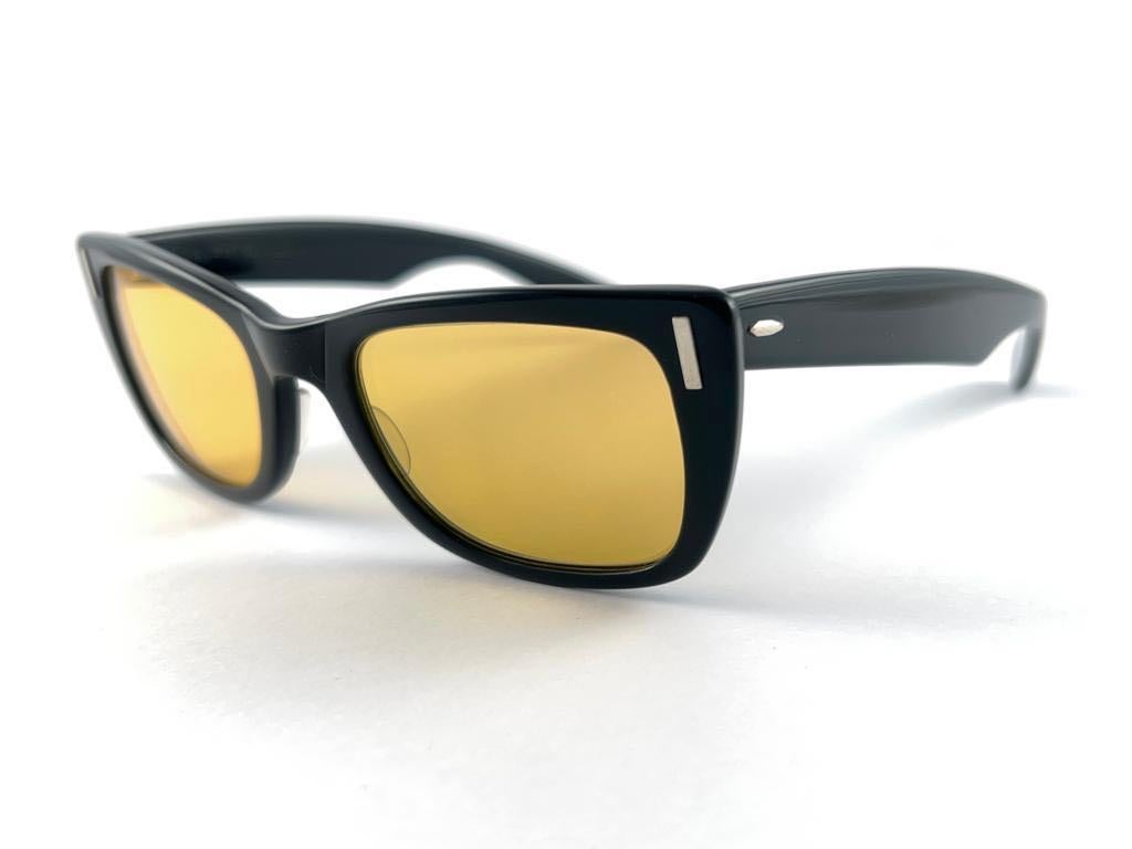 Super rare Ray-Ban des années 1960 de style Bob Dylan en noir élégant avec des accents argentés. Le grand artiste a porté ce modèle à plusieurs reprises entre 1960 et 1965.
Bausch and Lomb USA Made. Lentilles jaunes ambrées. Tout droit sorti des