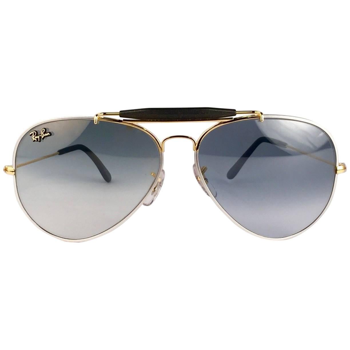 Objet de collection Métaux précieux Outdoorsman en 58Mm.
Le cadre est en plaqué or lourd 24 K combiné à du platine.  
Les lentilles sont d'un bleu étonnant avec un léger effet miroir. Le logo Ray-Ban se trouve sur le dessus de la lentille droite en