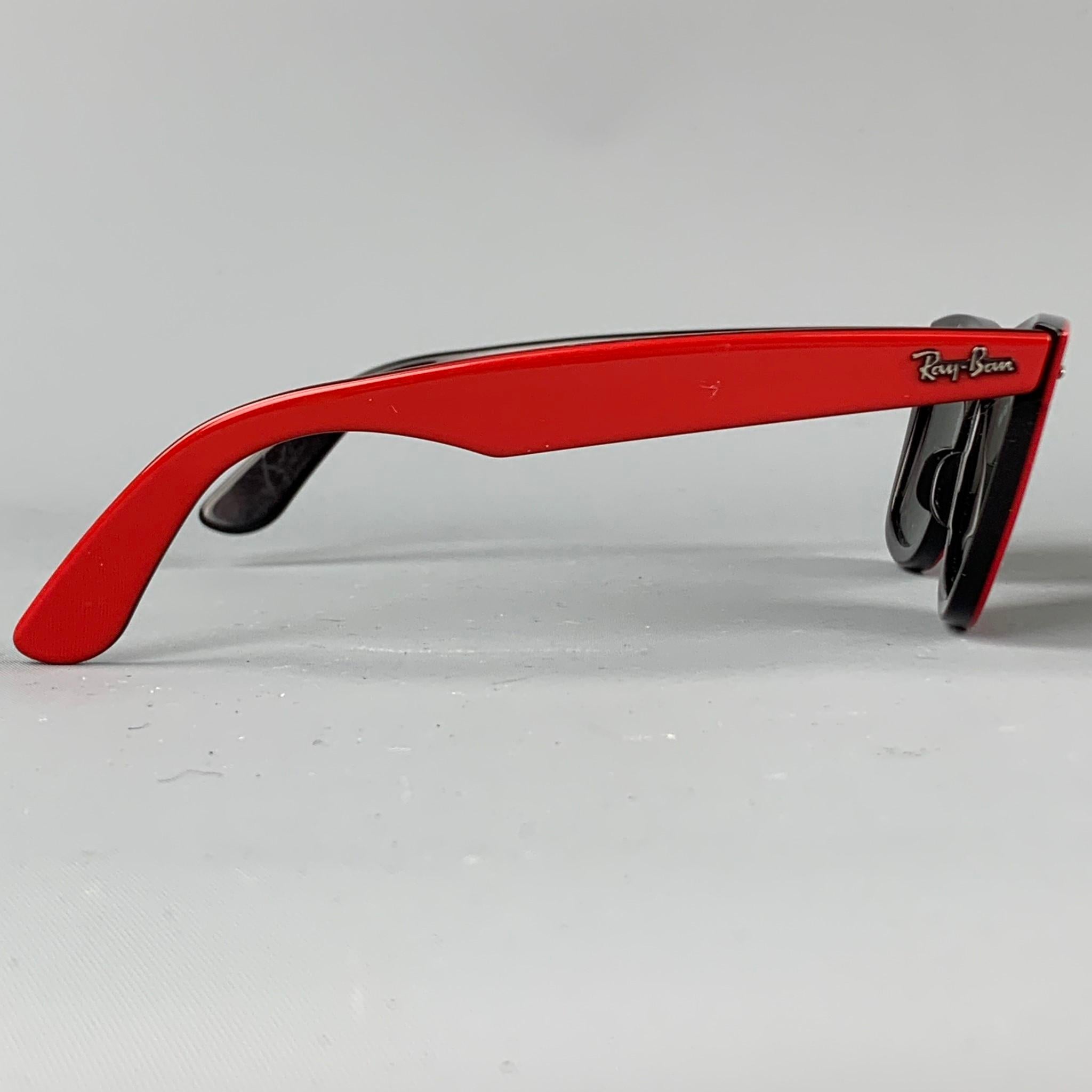 Vintage RAY-BAN sunglasses comes in a red acetate featuring a wayfarer style and black tinted lens. Comes with case. Hand made in Italy.

Very Good Pre-Owned Condition.
Marked: RB2140 955 50-22 3N

Measurements:

Length: 14 cm.
Height: 4.5 cm. 