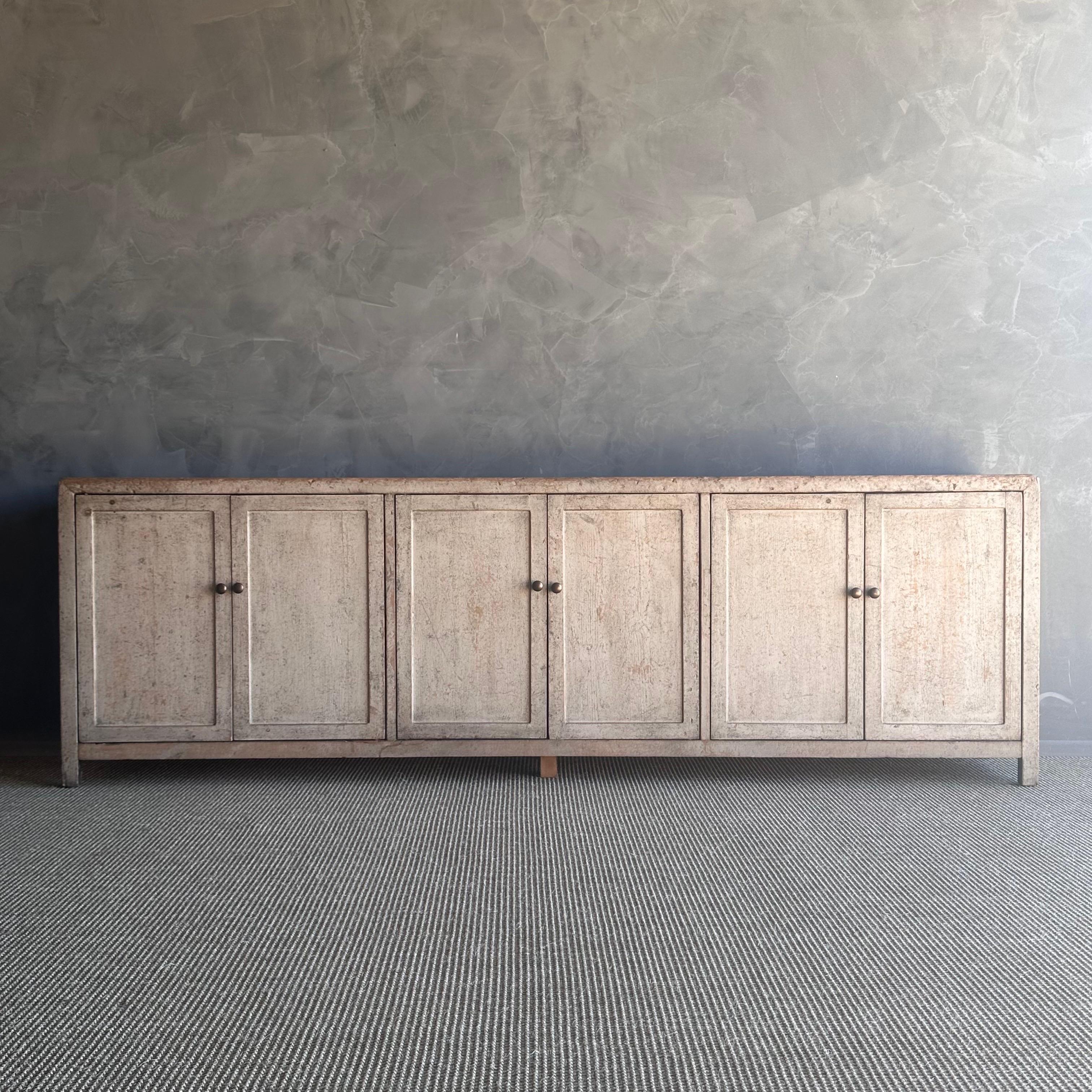 This stunning painted reclaimed pine cabinet features a gorgeous painted finish in a neutral tone, showcasing the original wood exposed underneath. With six doors offering ample storage space, this cabinet is both functional and stylish. The hidden