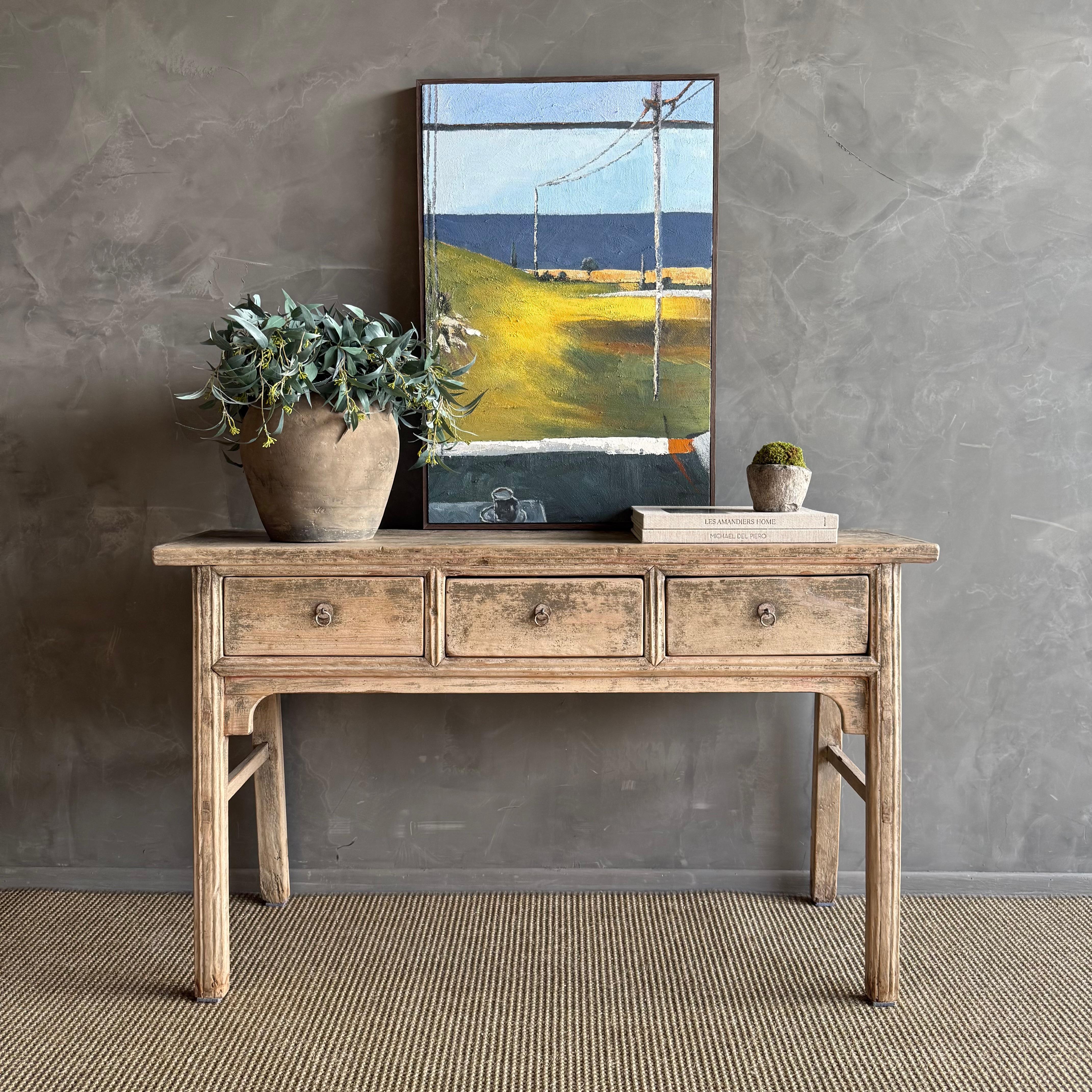 This charming vintage elm wood console is a one-of-a-kind piece with beautiful age and patina that adds character to any space. Its patina painted elm wood finish showcases the natural beauty of the wood, while the solid elm wood original hardware