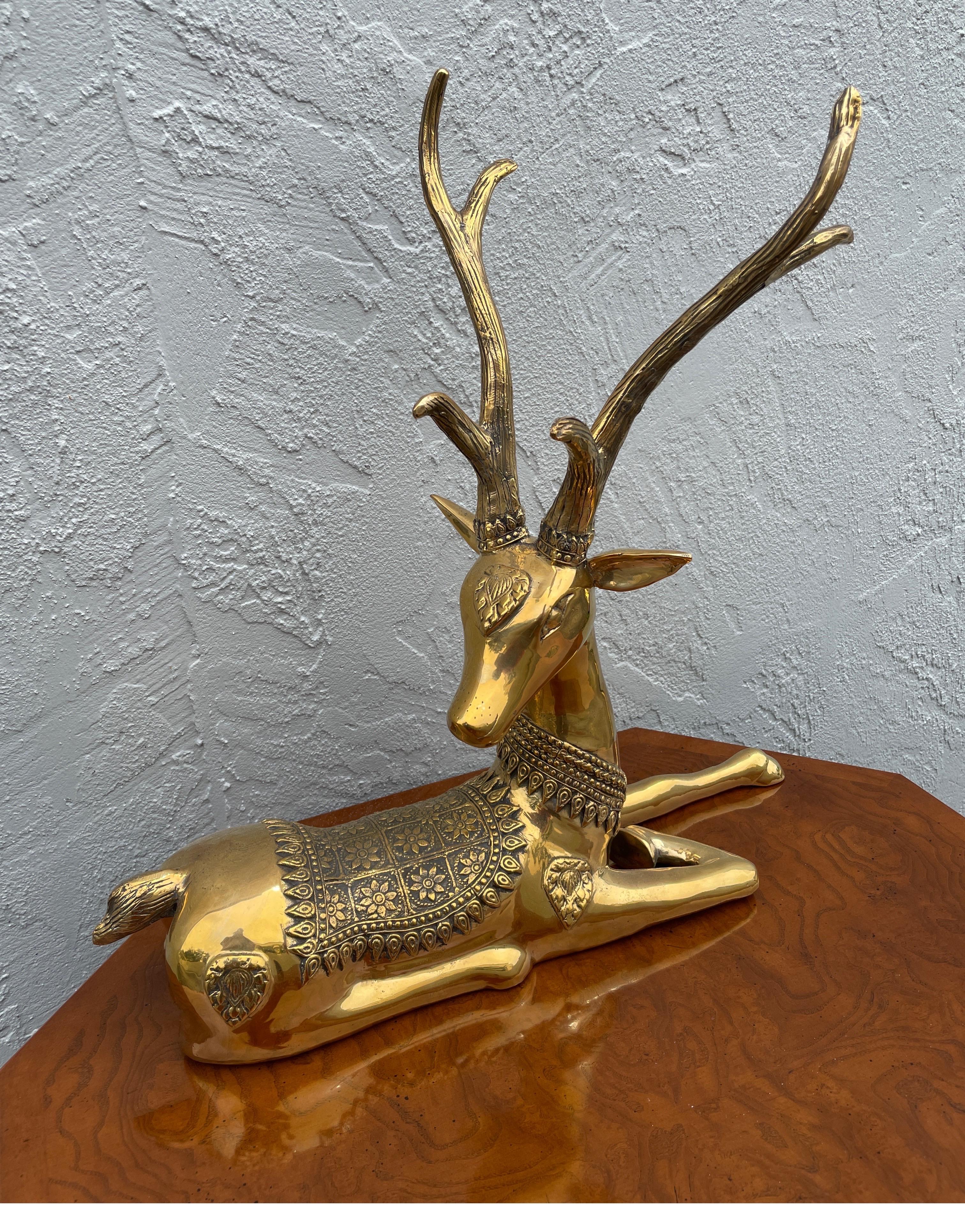 Decorative large polished brass seated deer sculpture.