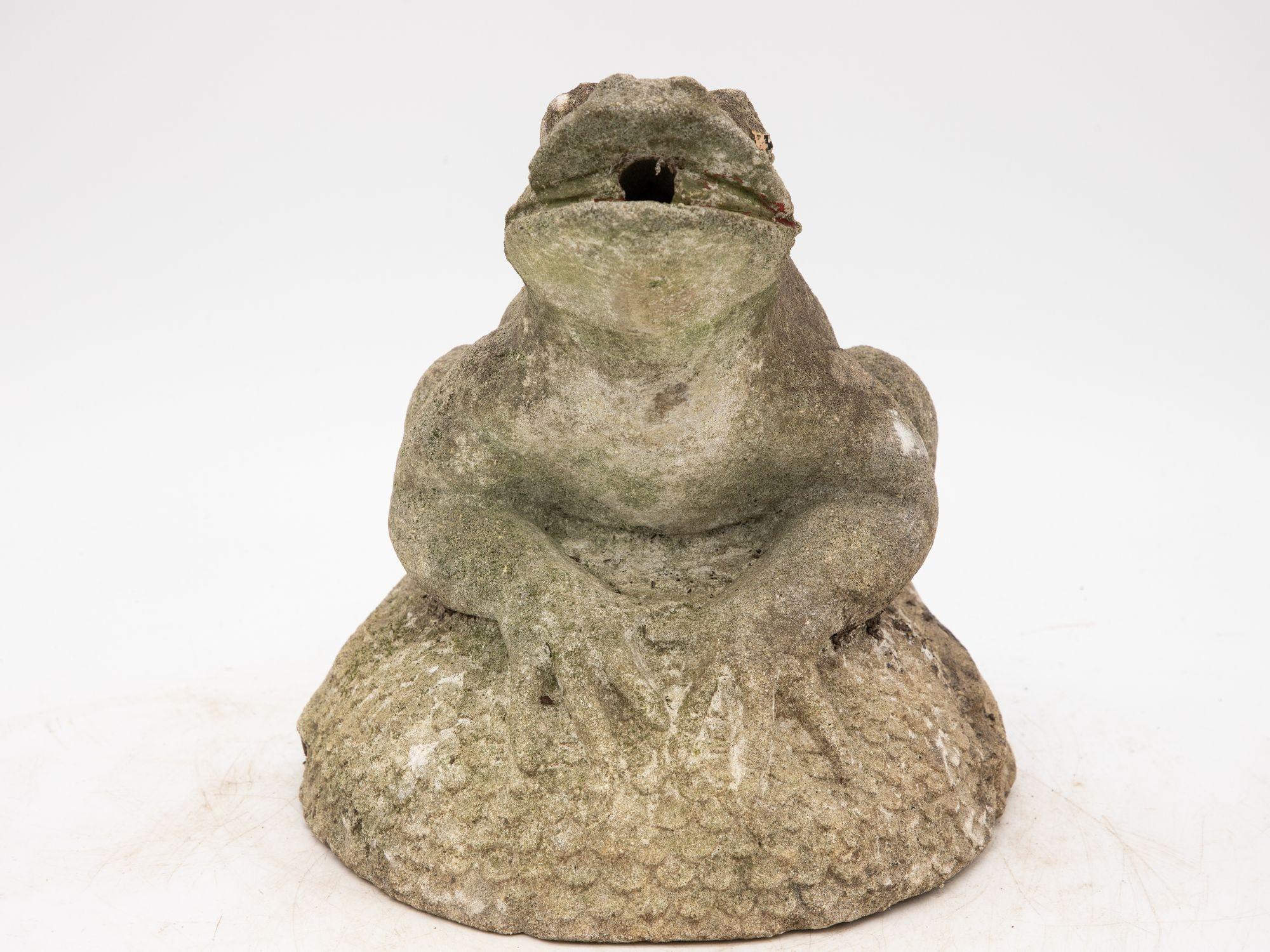The small concrete frog fountain is a delightful addition to any outdoor space, exuding whimsy and tranquility. With its charming design, it features a playful frog perched atop a pond rock. The rock displays an unusual fish scale pattern. This