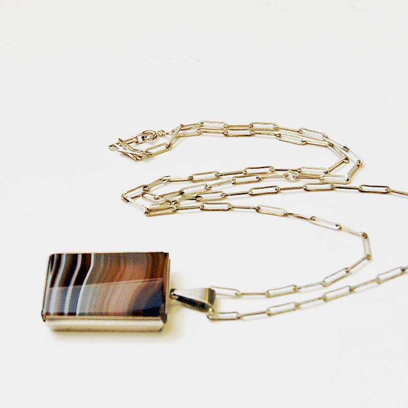 Una splendida collana in argento con pietra naturale e patina deliziosa proveniente dalla Svezia degli anni '70. Pietra naturale di agata marrone dai favolosi colori della terra circondata da una cornice in argento massiccio. L'armadietto può essere