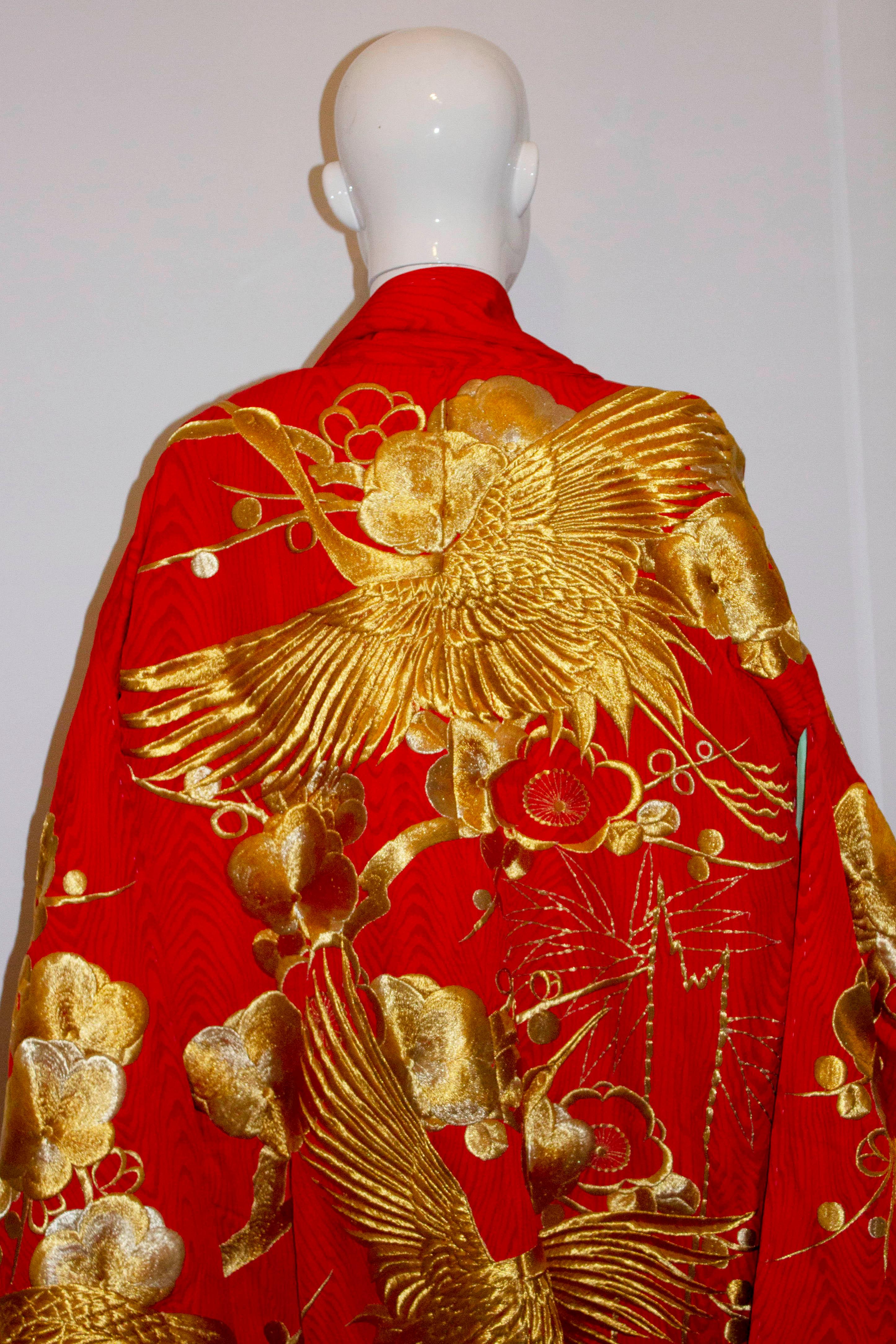 A stunning wedding kimono dating from the 1980s . In red shot silk with gold thread detail in the design of Cranes, Ume,/ Plum Blossom and Bamboo. Cranes mate for life and so are an auspicious symbol for a wedding kimono as they symbolize a long and
