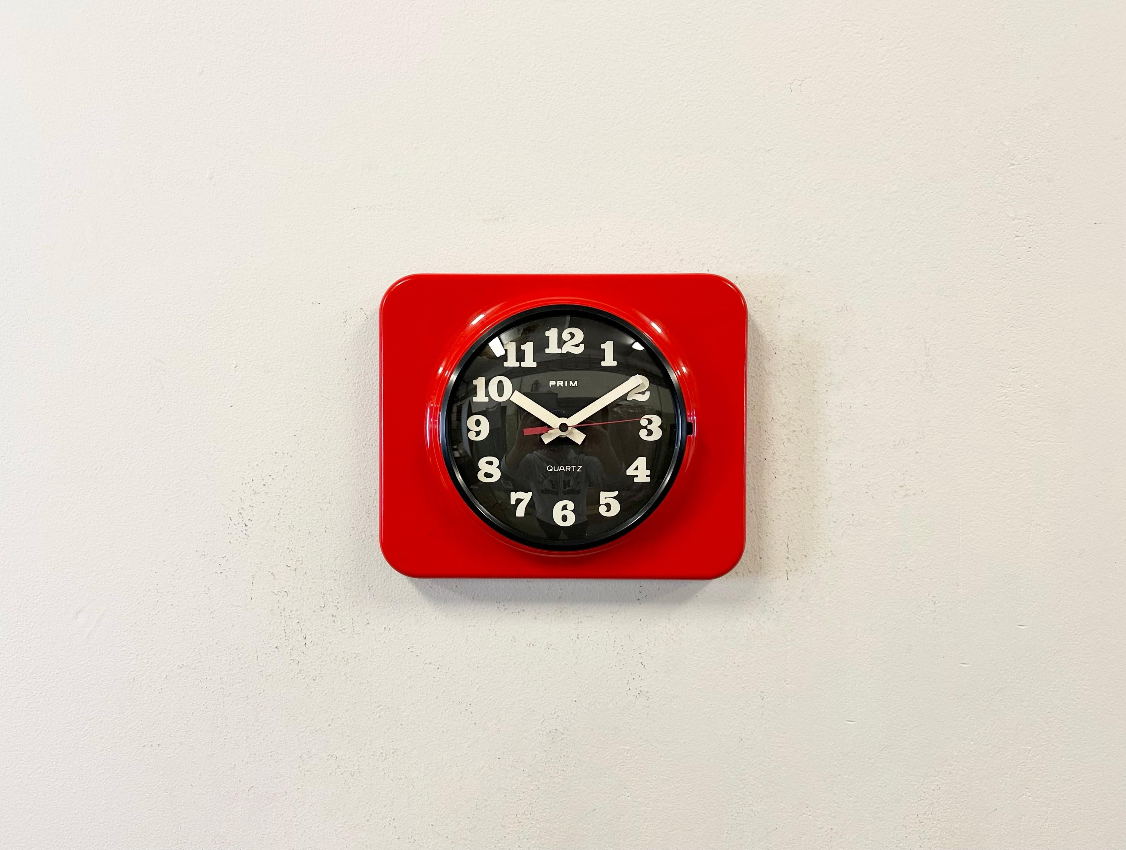 Vintge bakelite wall clock was made by Prim in former Czechoslovakia during tha 1970s - 1980s. It features a red bakelite body with black bakelite clockface and a convex clear glass cover. The original clockwork works perfectly and requires one C