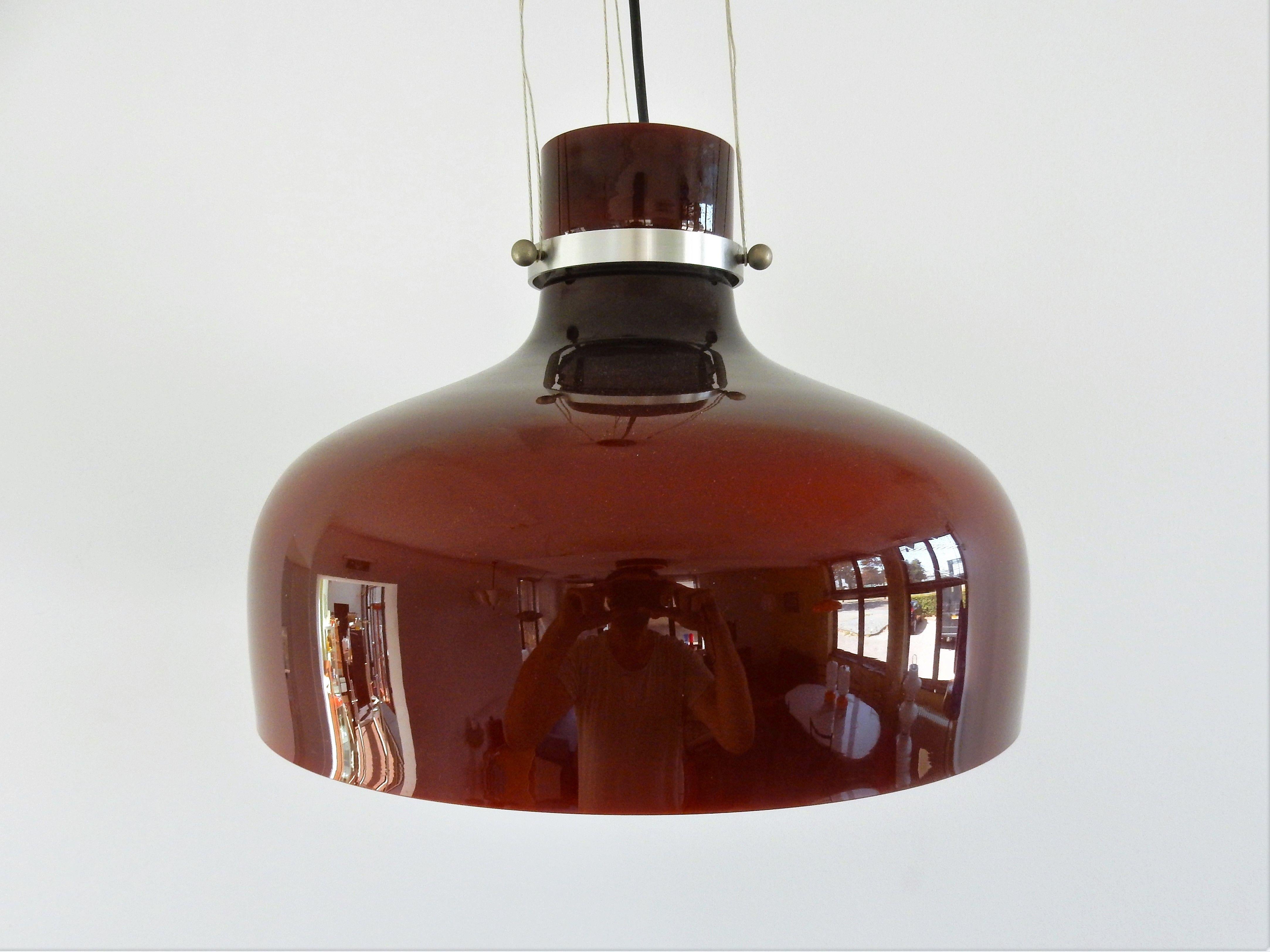 Diese große und sehr schöne Hängelampe ist aus rotbraunem Glas mit weißer Innenseite gefertigt. Das Glas wird mit einem Metallring und 3 Verbindungsschrauben an der Halterung aufgehängt. Dieses Modell ist im Katalog von Indoor dokumentiert, dann