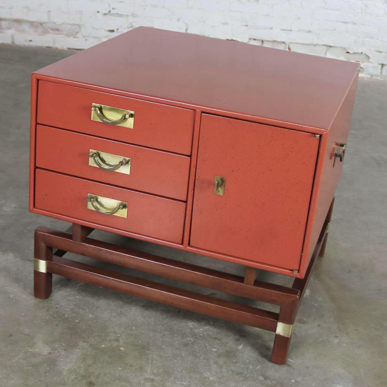 Incredible vintage Campaign style end or side table, maybe a nightstand, by Hickory Furniture Manufacturing. It is done in a gorgeous Chinese red finish for the box and stained butternut for the base with beautiful brass accents. It is in fabulous