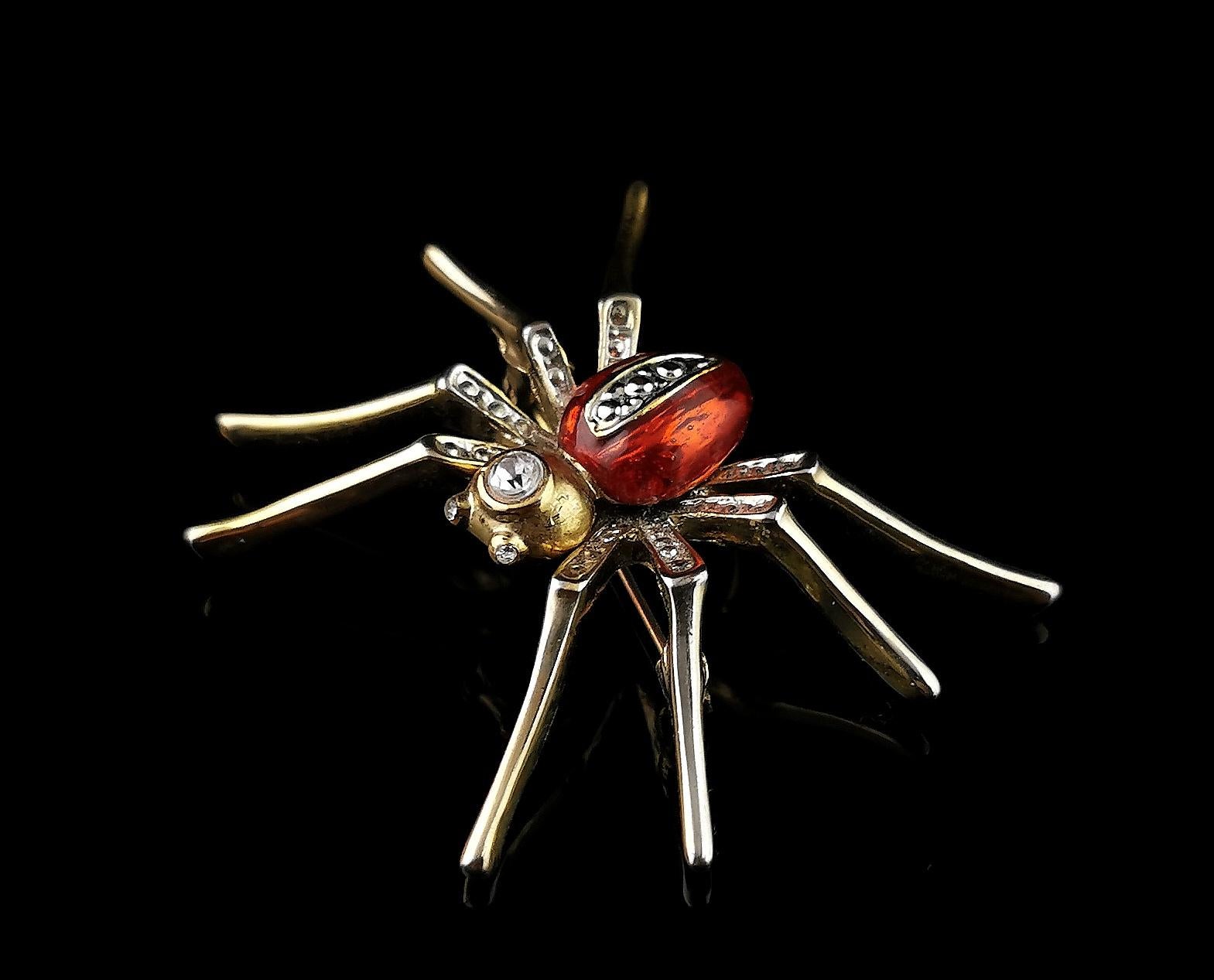 A fantastic large vintage spider brooch.

Crafted in a rich gold tone metal, it is a good sized piece, well designed and it is set with sparkling diamante to the body and eyes.

The spider body is finished in a lovely red enamel which sets of the