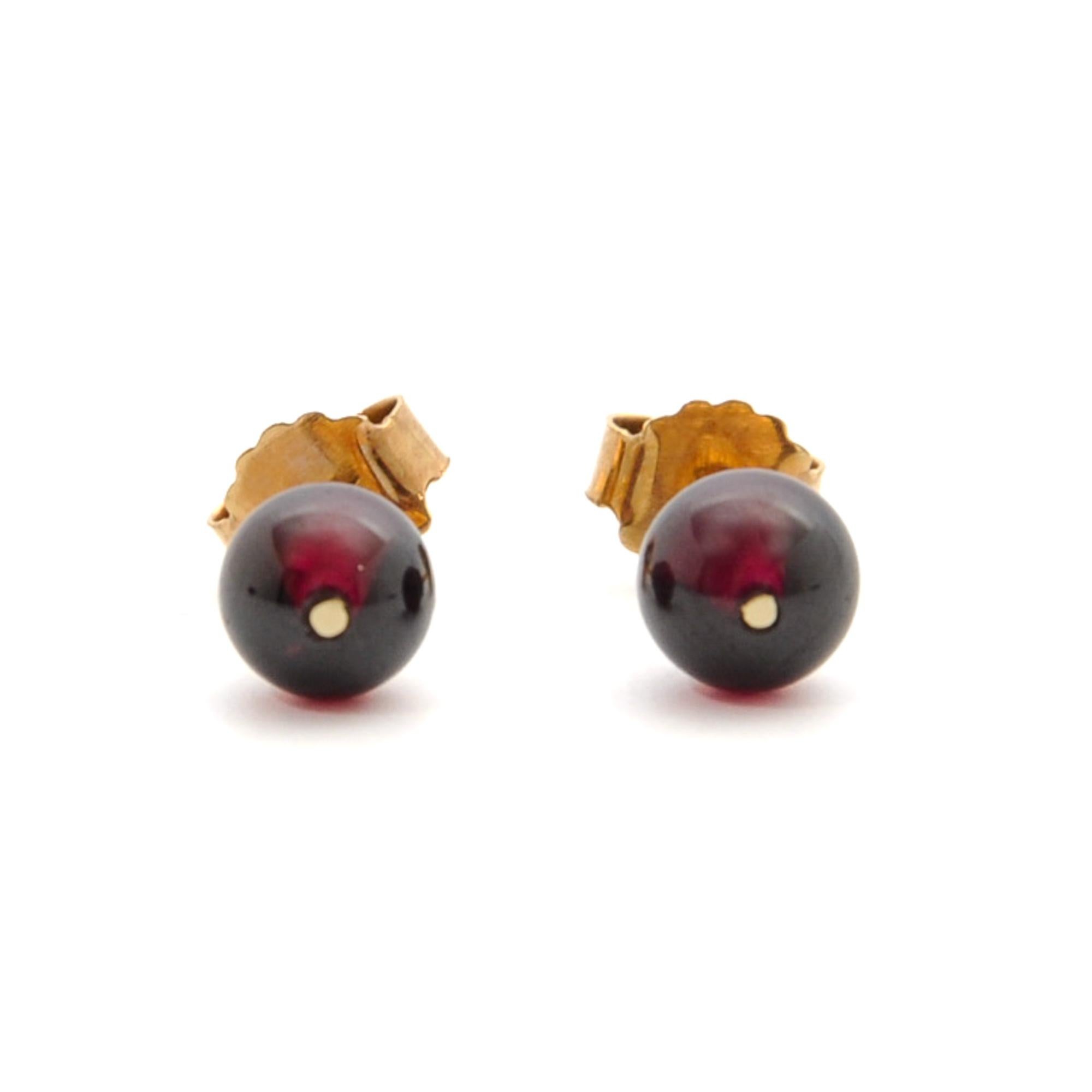 A gorgeous pair of natural round bead red garnet stud earrings. The smooth round garnet is attached to a 14 karat gold setting on the back, which has a beautiful round cannelure ornament. The garnet stones have a nice deep red color and the studs