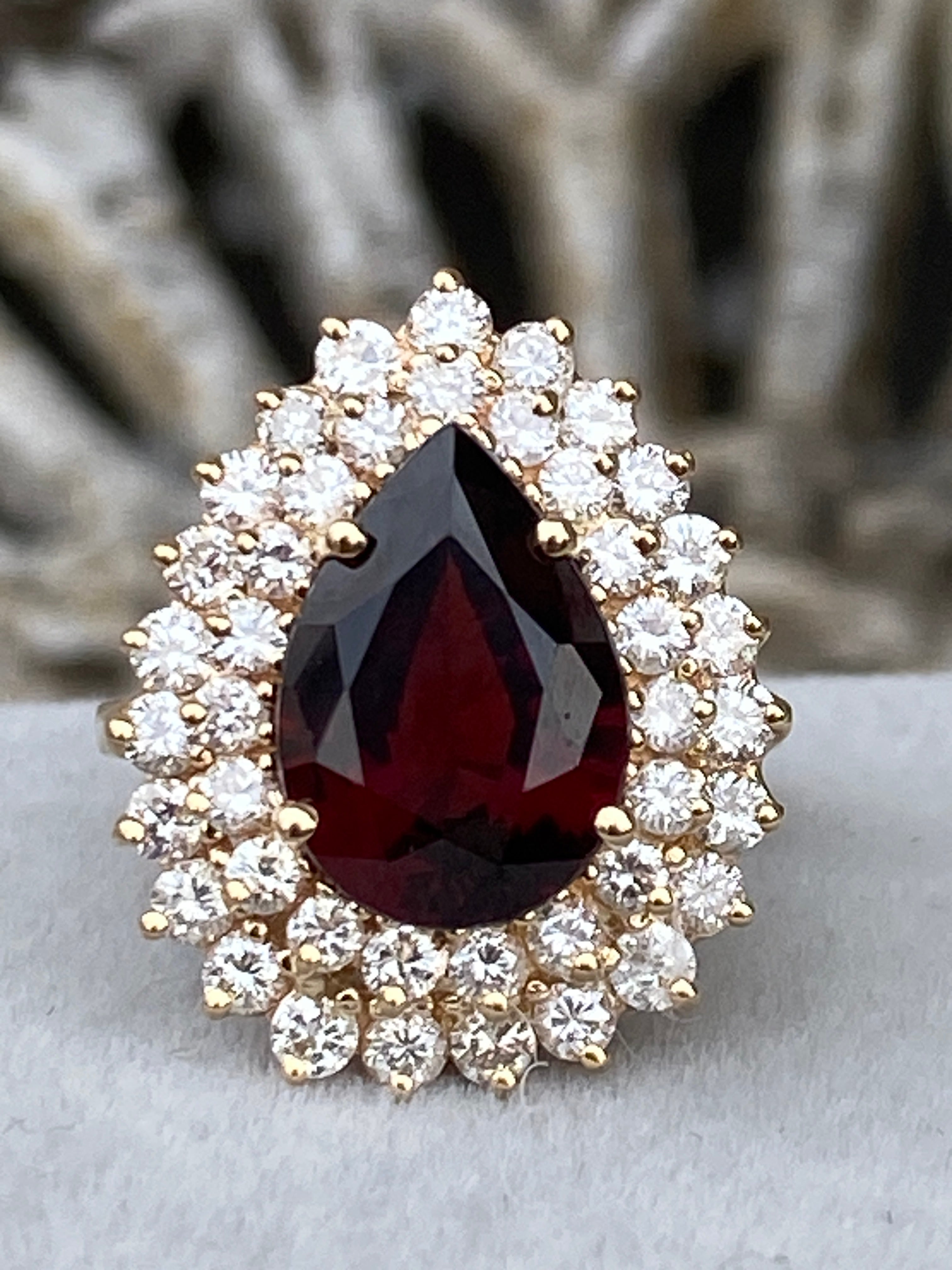 We instantly fell in love with showstopper of a ring as soon as we saw it.  It features a beautiful natural pear shaped faceted red garnet at the center surrounded by a double halo of sparking natural near colorless diamonds. Crafted in 14 karat