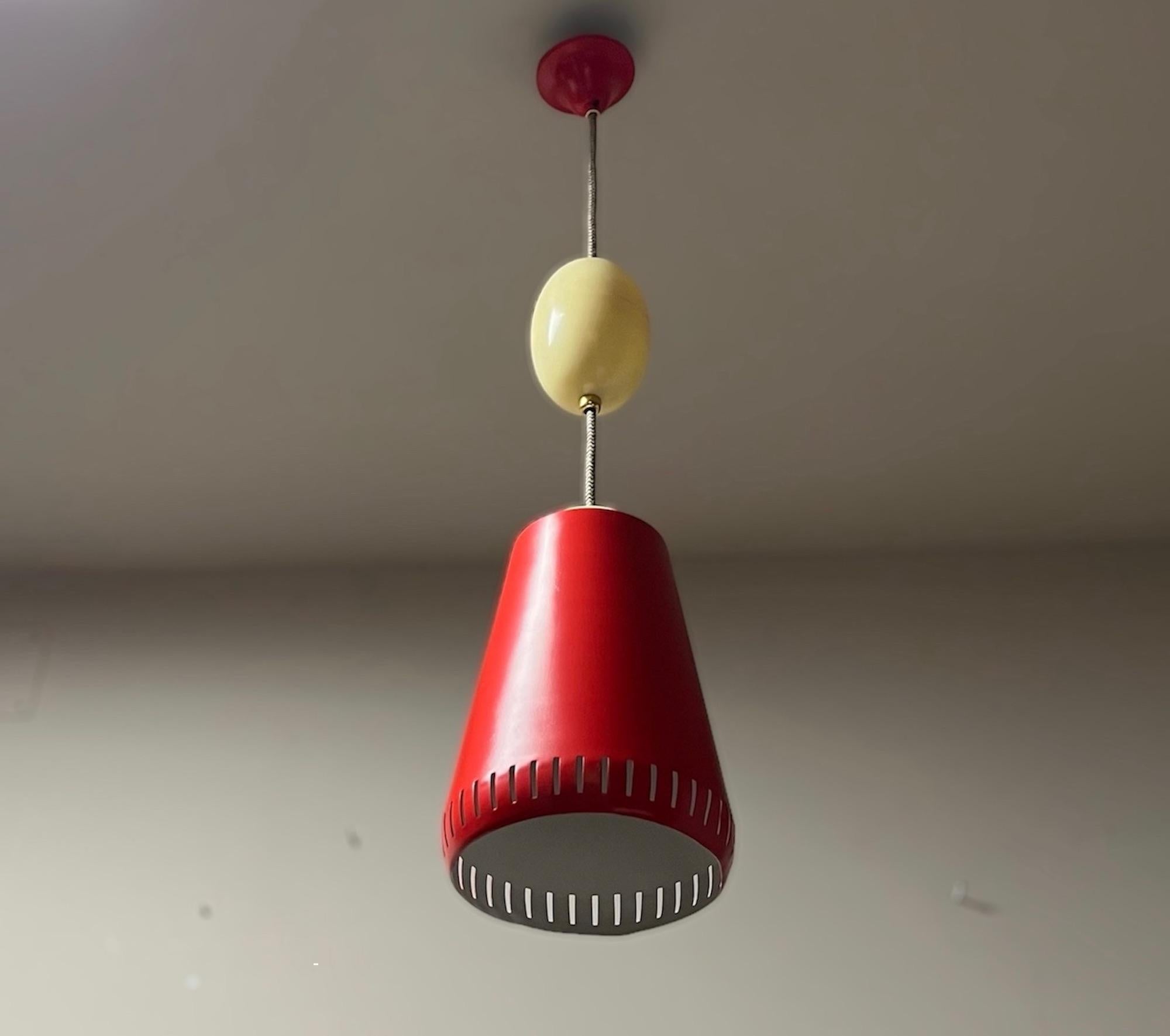 A lovely hanging lamp by Stilnovo, with all the charm of the 1960s. The orange lampshade made of metal with the distinctive Stilnovo rectangular holes matches perfectly with the beige plastic parts.It has an original switch on the top of the