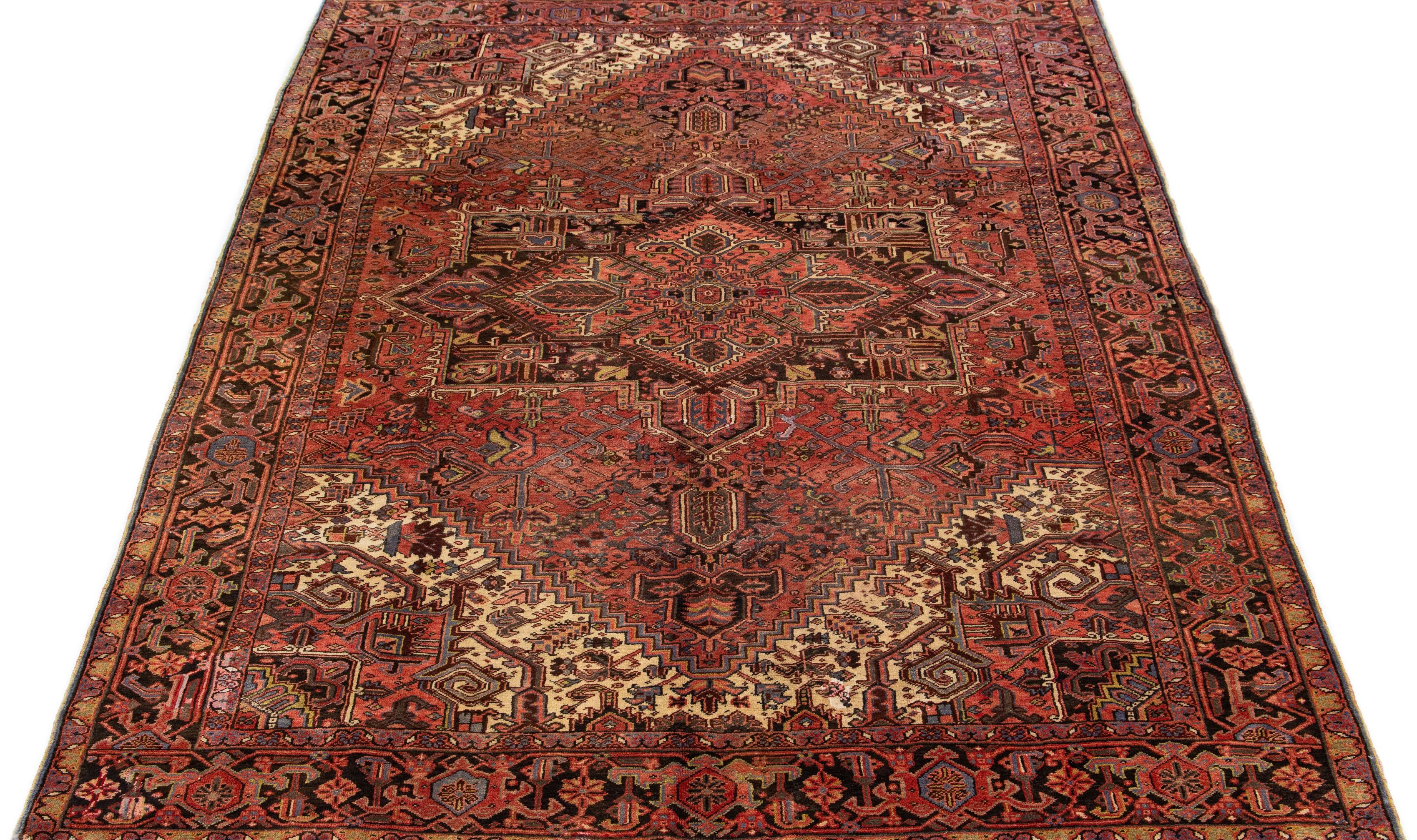 Beautiful vintage Heriz hand knotted wool rug with a red-rust color field. This Persian rug has multi-color accents in a gorgeous all-over geometric floral medallion design.

This rug measures 8'1