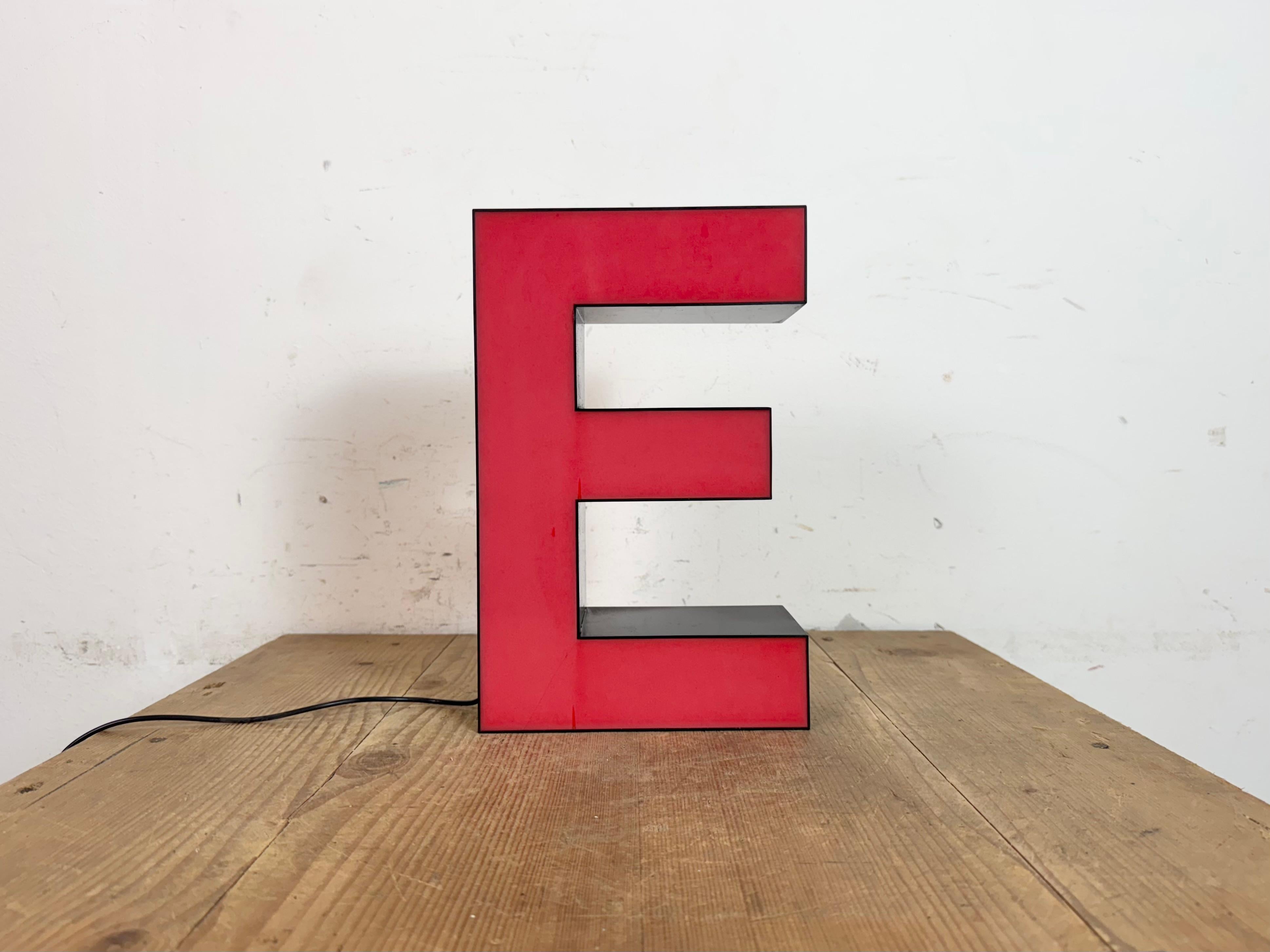 Dieser Vintage-Industriebuchstabe E mit roter Beleuchtung wurde in den 1970er Jahren in Italien hergestellt und stammt von einem alten Werbebanner eines alten Teppichgeschäfts in Turin. Es hat einen schwarzen Eisenrahmen mit roter Kunststoffschrift.
