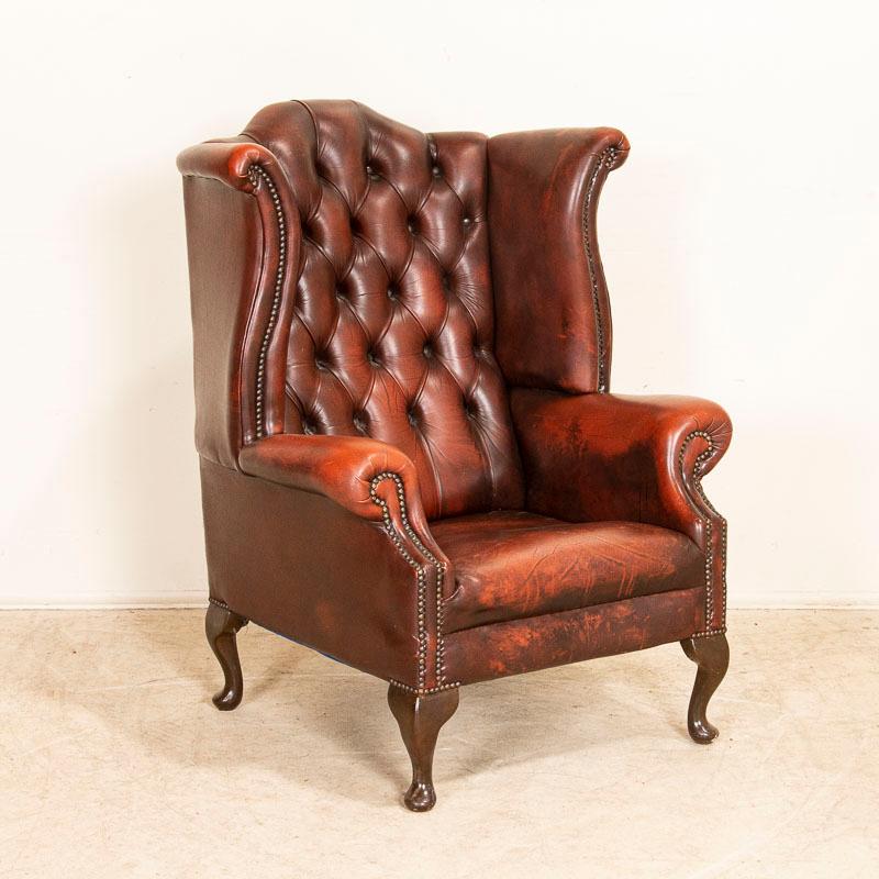 Whether you are ready to read a good book or smoke a cigar, this chair invites one to sit down and relax. This handsome wingback armchair has a high tufted back with rolled arms while the mottled red leather is in well-kept original condition.
