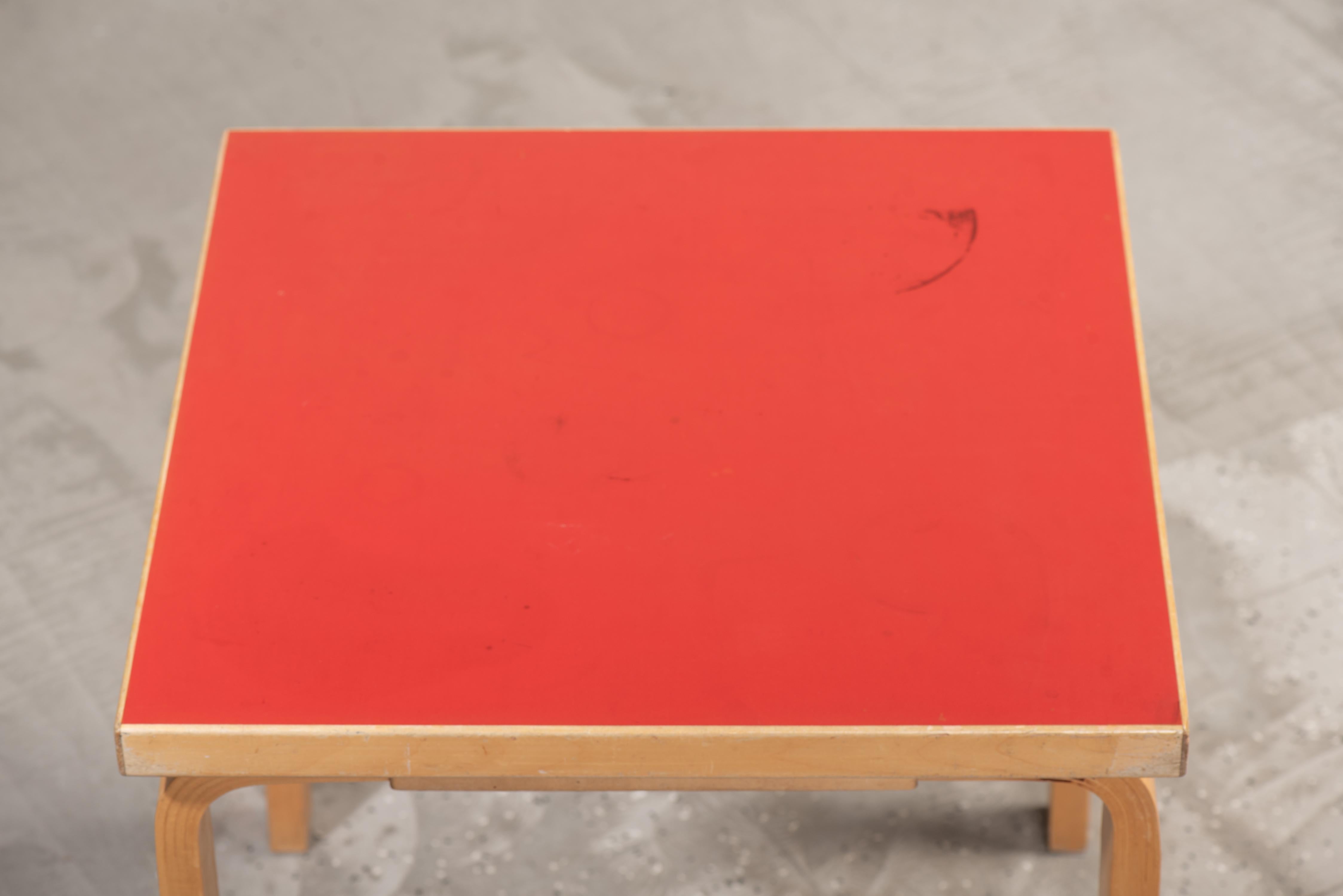 Une table carrée 81C magnifiquement travaillée, conçue par Alvar Aalto. Produite par Artek dans les années 1950, cette table présente un plateau en linoléum rouge vif et des pieds en bouleau cintré stratifié. Le cadre robuste a été construit en