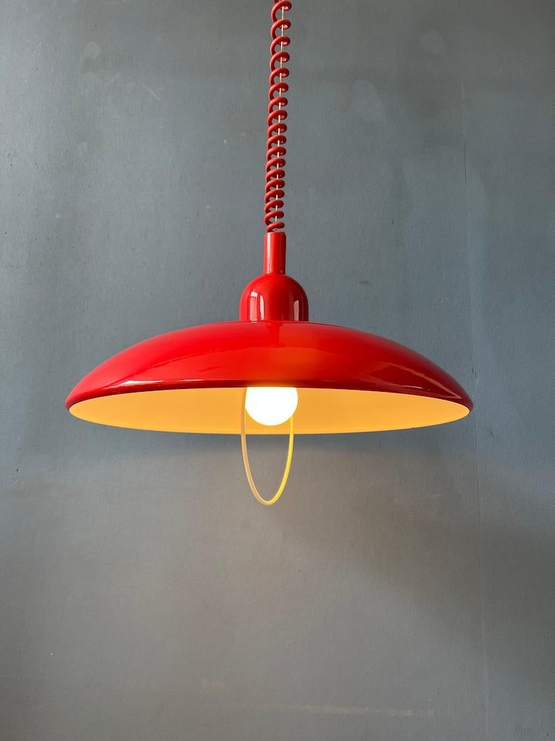 Beautiful red vintage pendant lamp. The lamp has shiny red lacquer. It can easily pulled up and down with the rise-and-fall mechanism. The lamp is made out of metal and has a plastic top and ceiling cap. The lamp requires one E27 lightbulb and