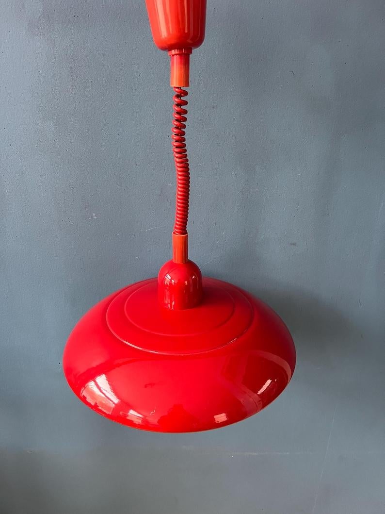 Belle lampe suspendue vintage rouge en métal. La lampe est recouverte d'une laque rouge brillante. Il peut être facilement tiré vers le haut et vers le bas grâce au mécanisme de montée et de descente. La lampe est fabriquée en métal et dispose d'un
