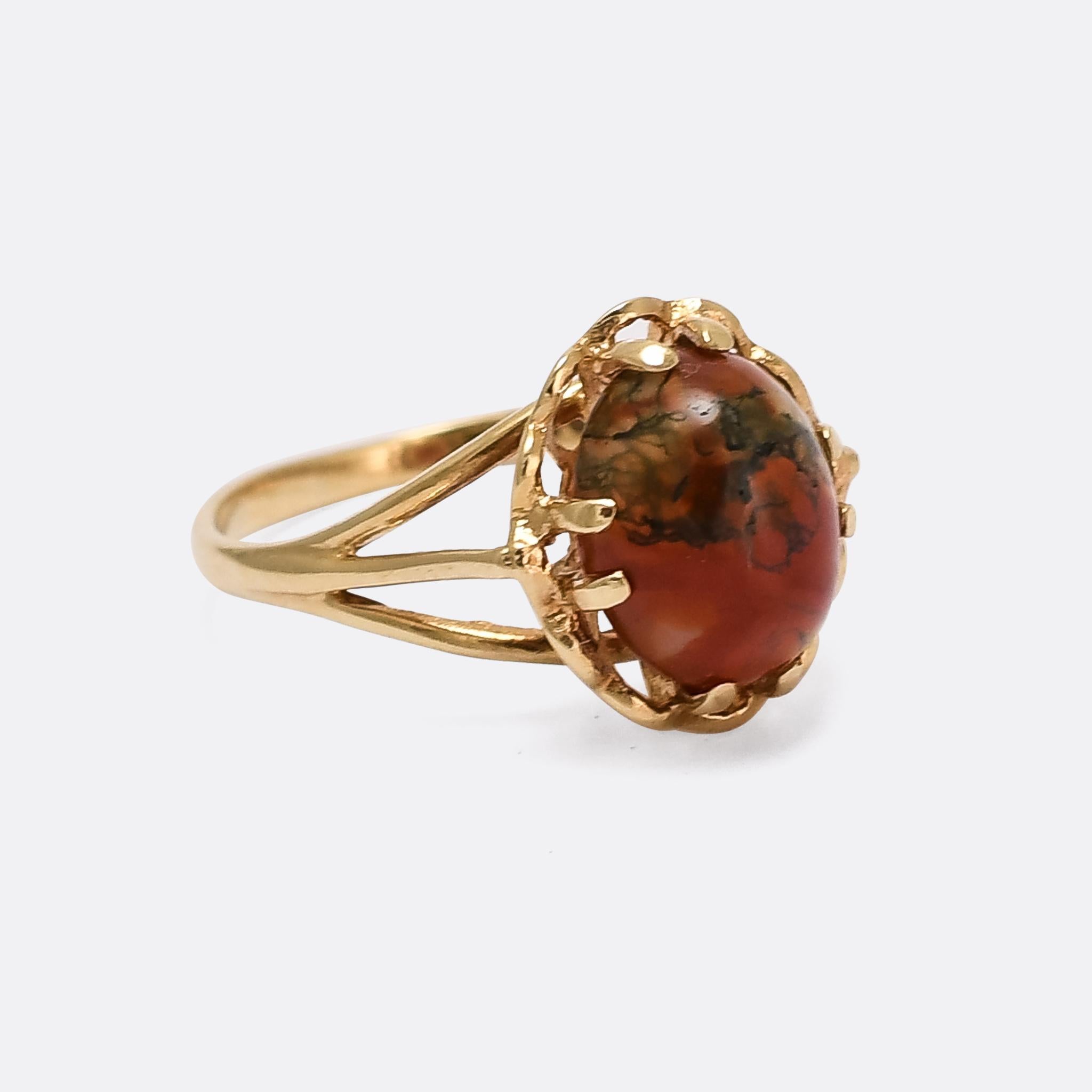 A striking vintage single-stone ring set with a red moss agate cabochon. The stone rests in an eight-claw mount with an openworked flower petal design behind, and elegant trifurcated shoulders. It's modelled in 9 karat gold with clear Birmingham