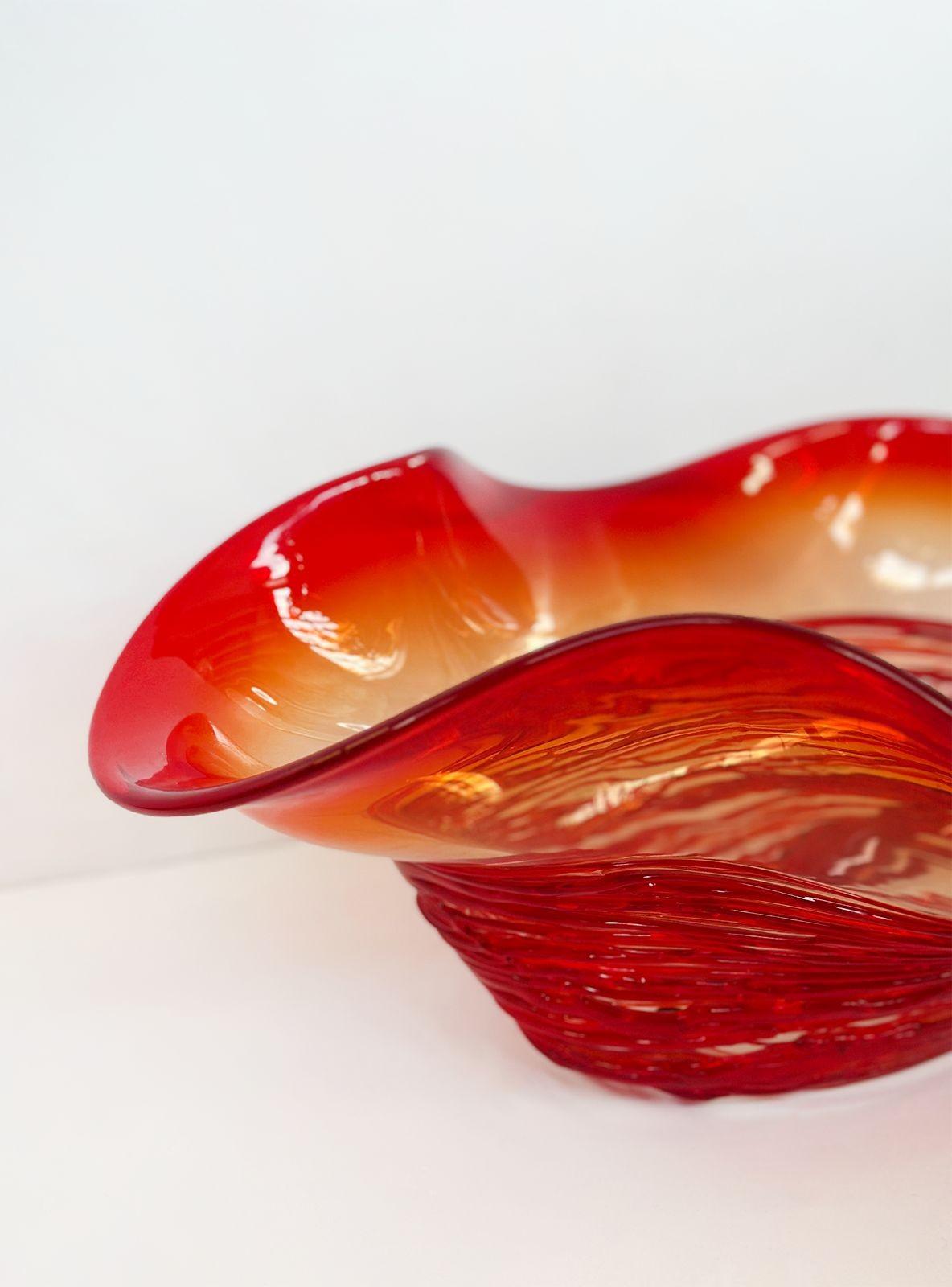 Stunning vintage red Murano glass bowl made by Camozzo during the 1970's. This exquisite piece showcases vibrant red tones, accentuated by subtle orange details that gracefully blend together, creating a captivating visual appeal. The bowl's unique