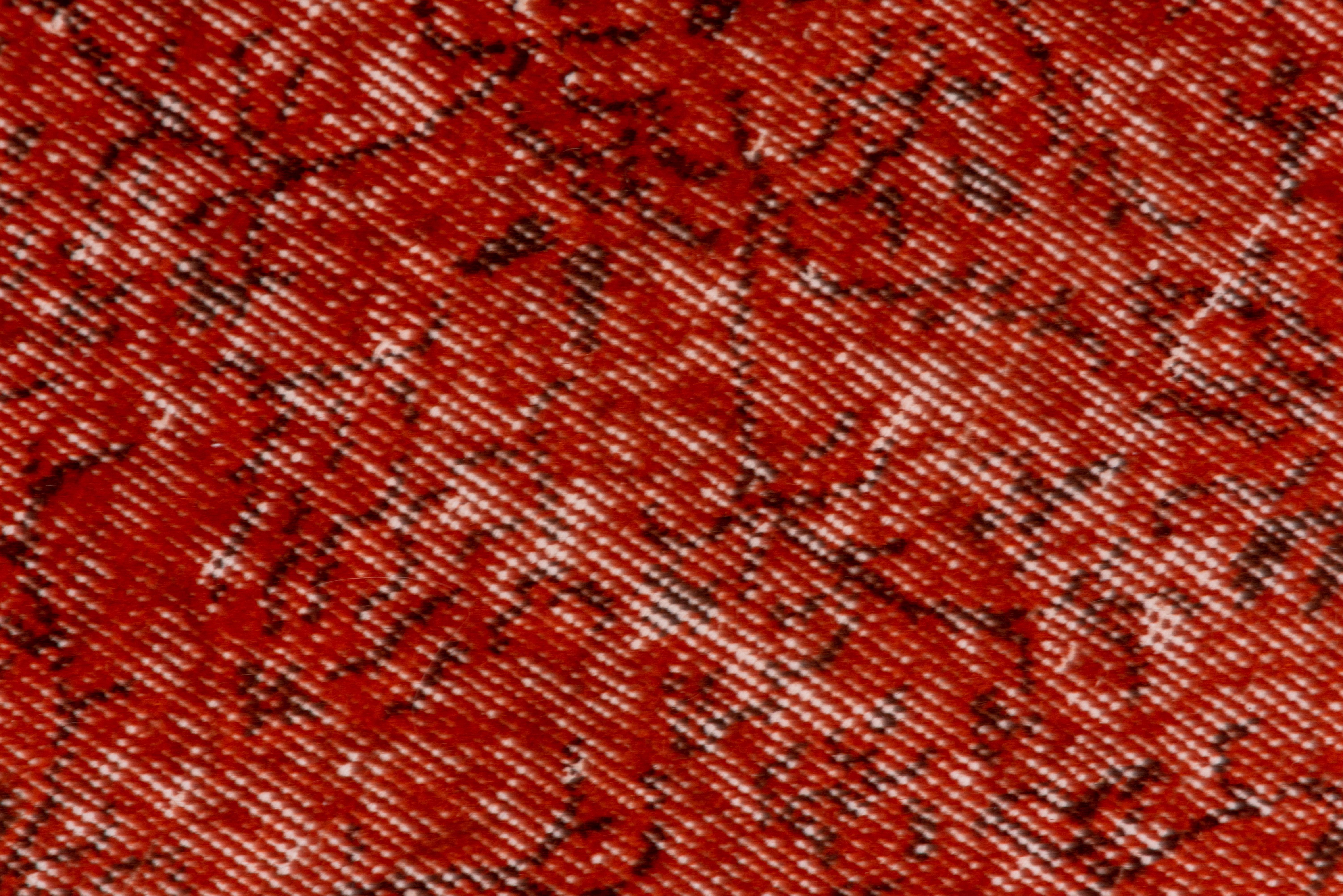 This distressed and orange-red overdyed carpet shows several random vertical, ecru zig-zags dominating a black squiggle pattern. A strong color splash.