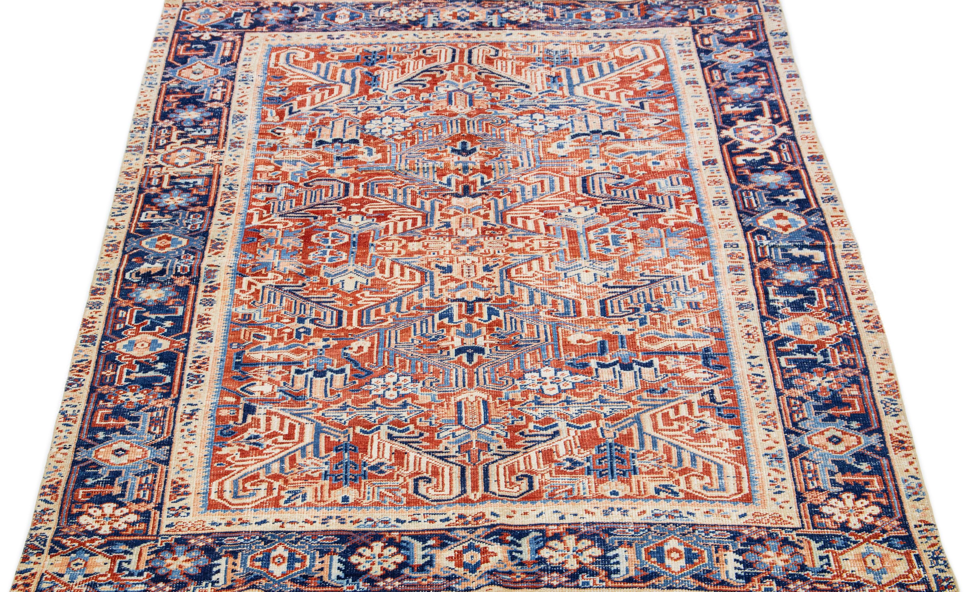 The antique Heriz rug exudes timeless elegance and sophistication with its premium hand-knotted wool and striking all-over design. The eye-catching geometric floral pattern in shades of blue and beige adds a touch of allure to the soft peach field,