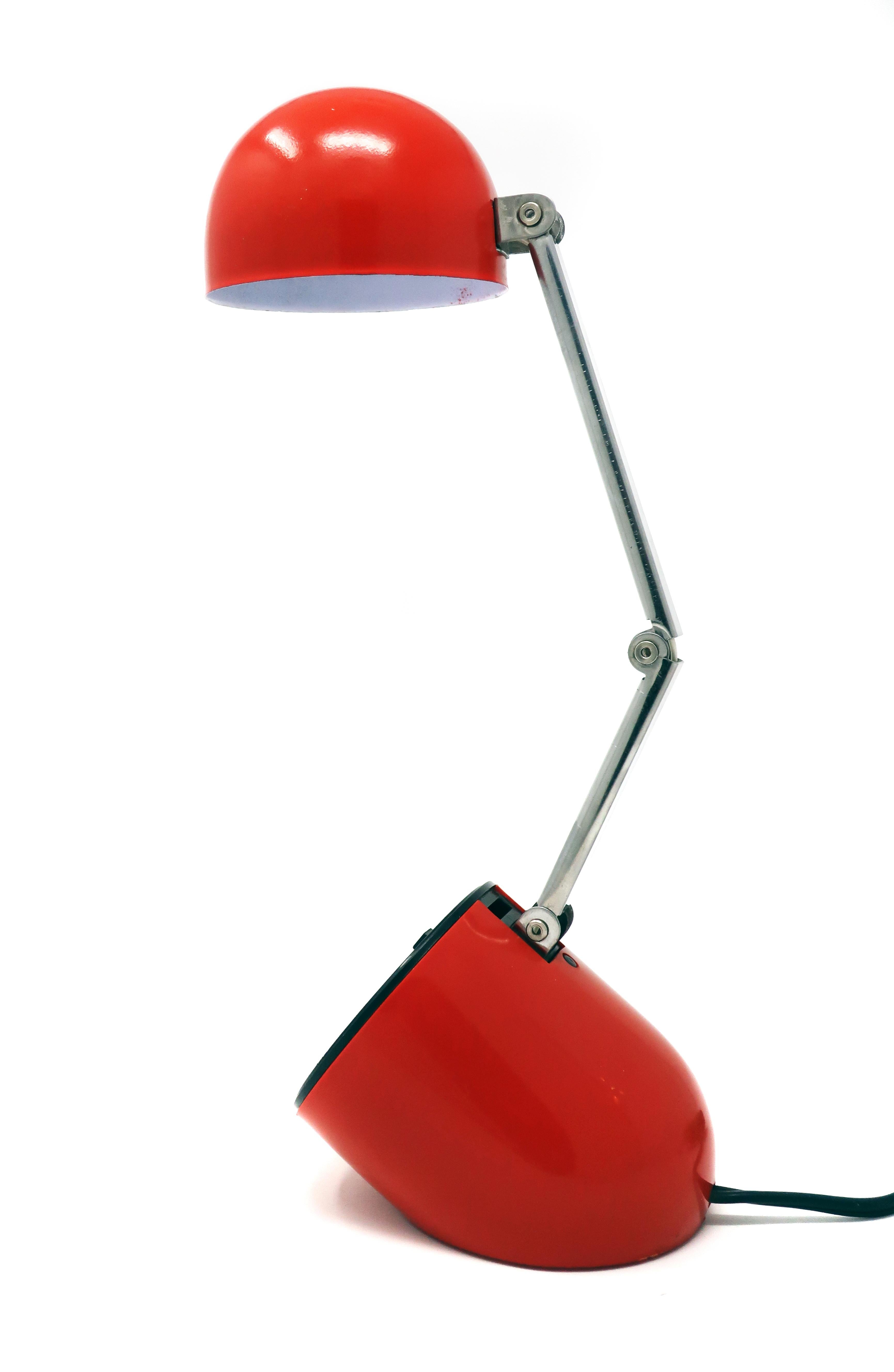 A Classic of Mid-Century Modern lighting design, this small lamp unfolds from a perfect pill shape into a perfect desk lamp. Red base and shade, chrome stem, and 2 intensity switch on base. In excellent vintage condition with one small mark on the