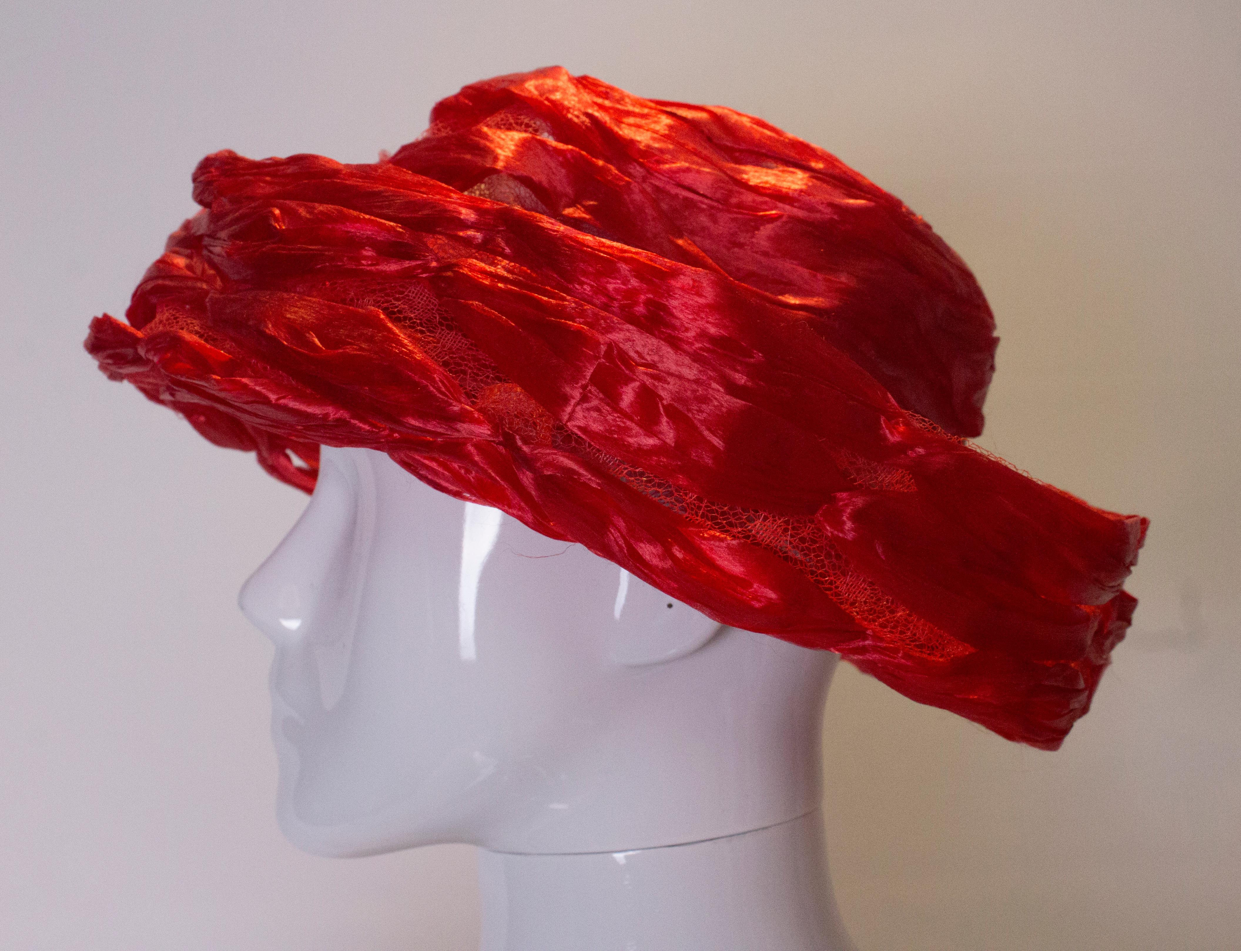 A chic vintage red hat by Fenwicks. The hat is made of ribbon and net with an inner circumference  of 25''.
