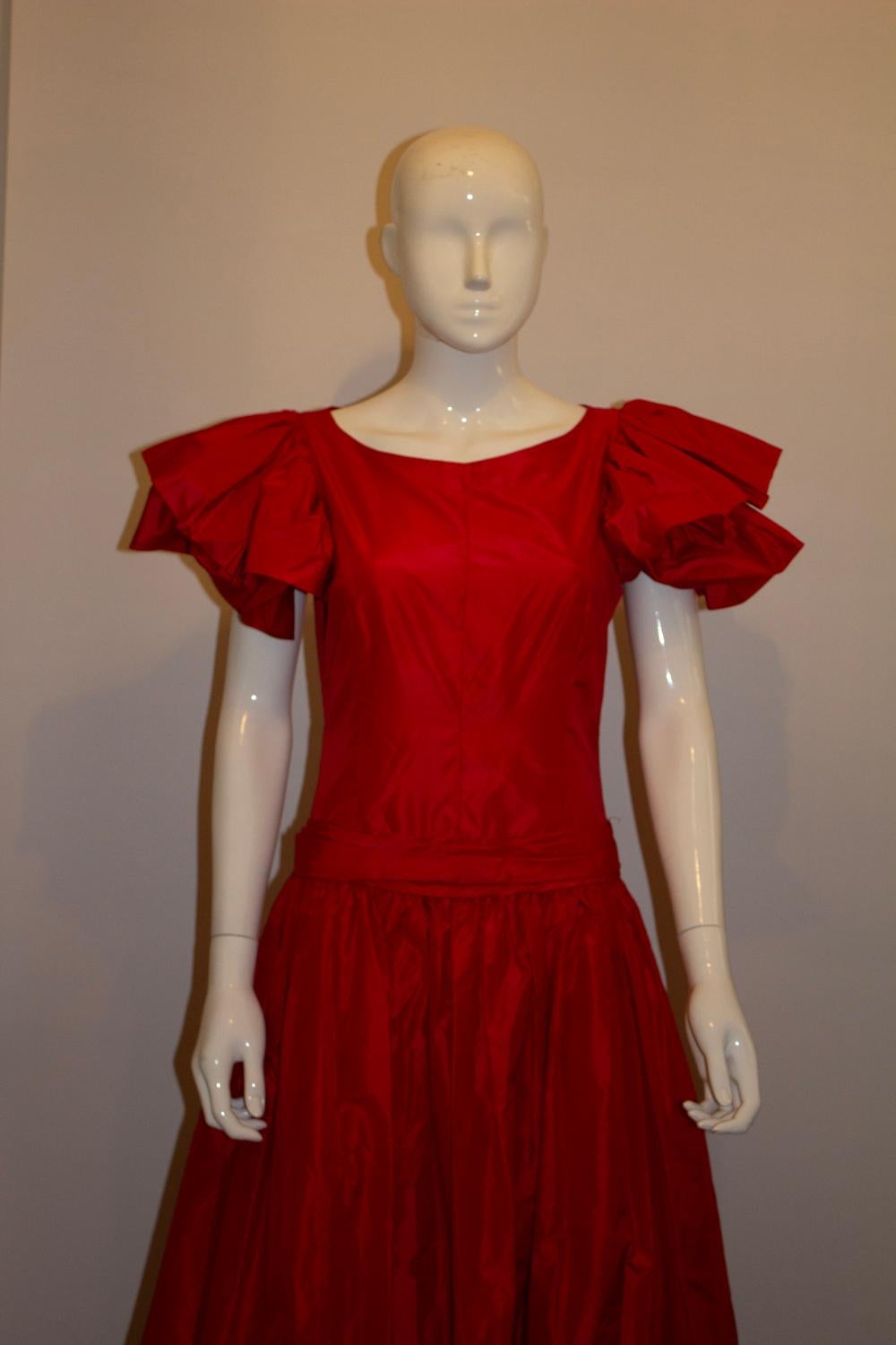 A stunning vintage silk evening gown in a vibrant shade of red. The dress has frill cap sleaves, a drop  waist and a central back zip. It has a built in petticoat.
Measurements, Bust 37'' waist 30'' ,length 59''