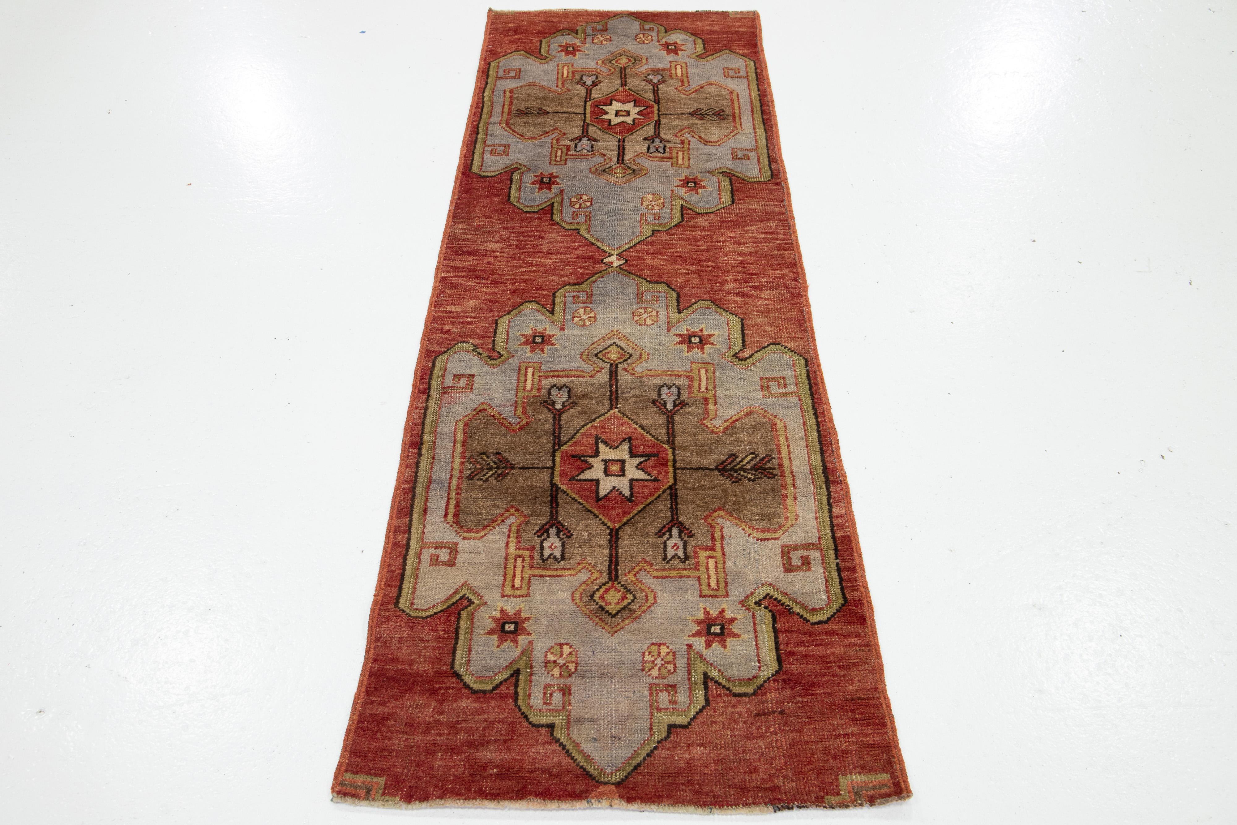 Ein wunderschöner türkischer Läufer im Vintage-Stil zeigt ein rotes Feld mit einem geometrischen Stammesmuster, das sich über den gesamten Teppich erstreckt und durch hellbraune und graue Akzente ergänzt wird.

Dieser Teppich misst 2'4