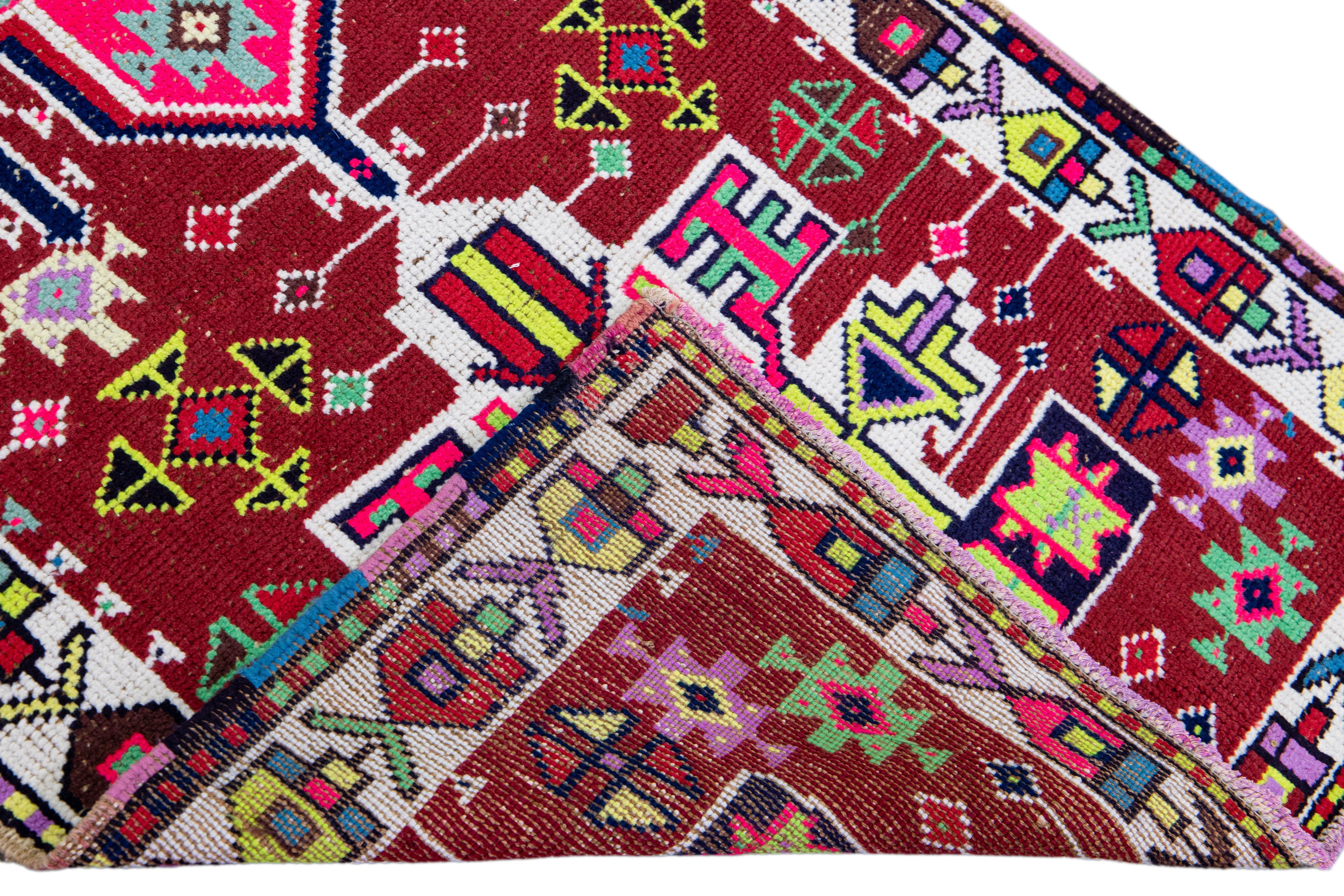 Beautiful vintage Turkish hand-knotted wool rug with a red field. This rug has a white designed frame and multicolor accents in a gorgeous all-over geometric tribal design.

This rug measures: 2'8