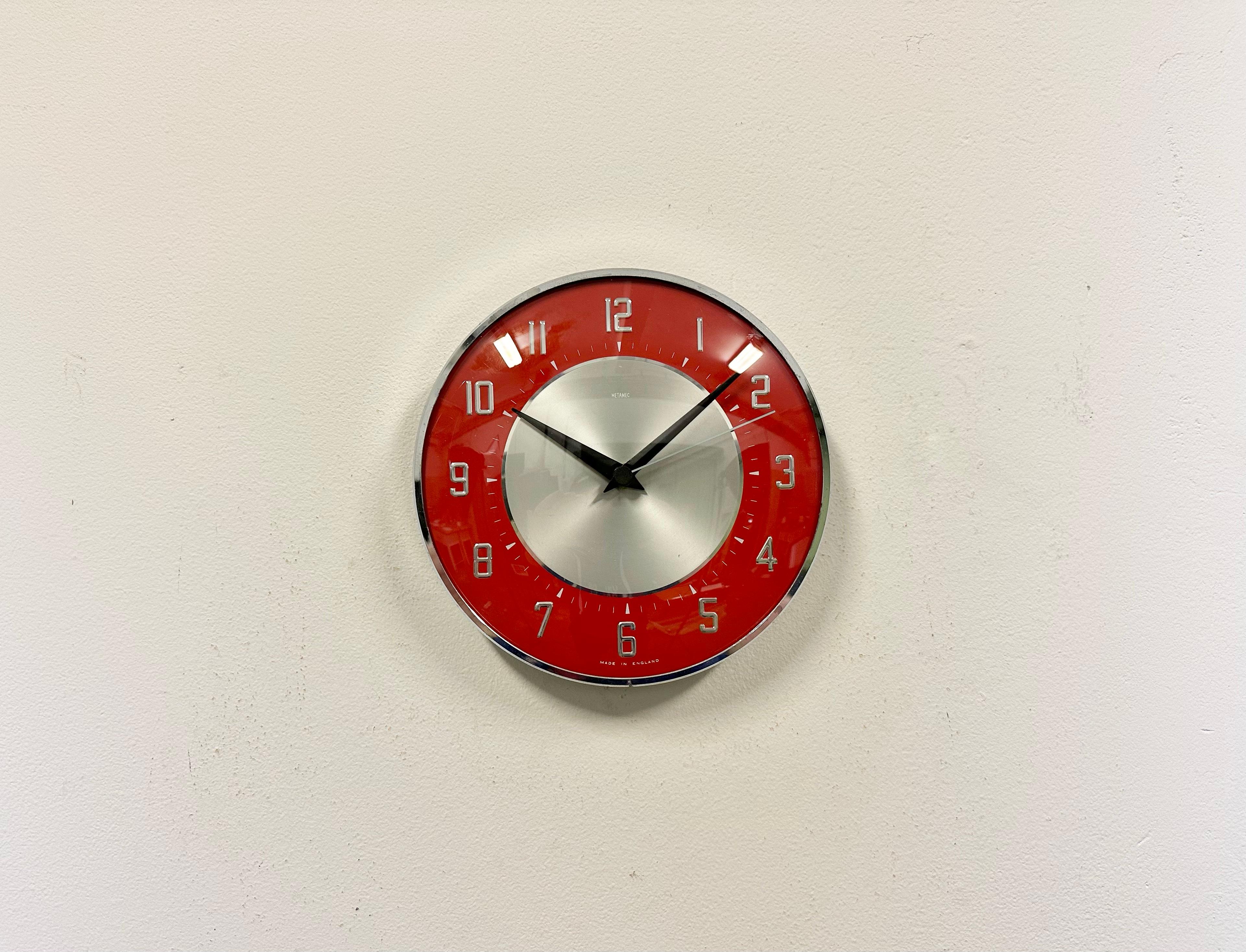 Wall clock produced by Metamec in England during the 1970s. It features a red-silver bakelite clock face,a chrome-plated frame and a convex clear glass cover. The piece has been converted into a battery-powered clockwork and requires only one