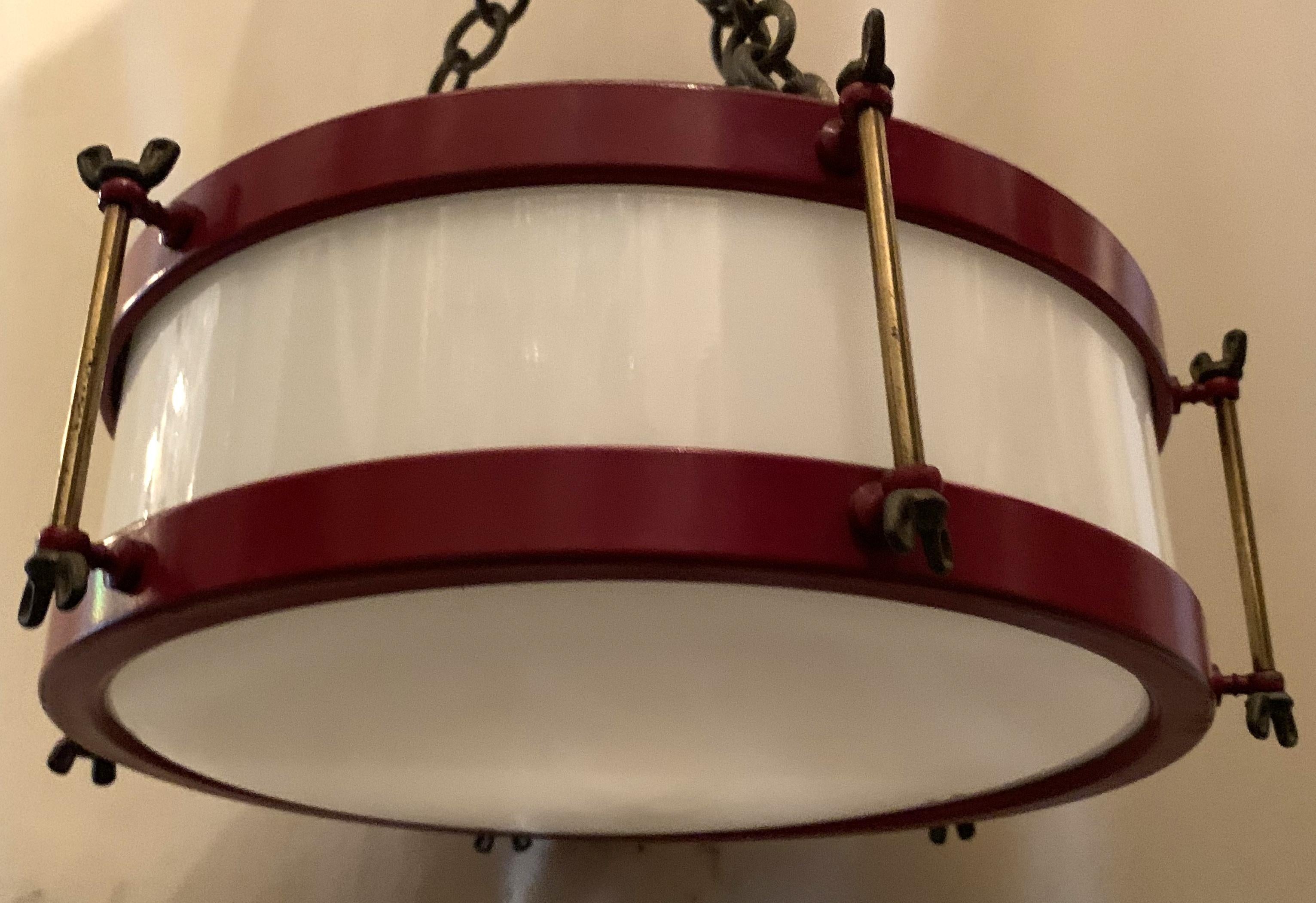 A whimsical vintage red enamel painted and white glass bronze mounted snare drum form flush mount light fixture with rewired Edison light bulb leading down from 3-rope twist chains. Currently 15