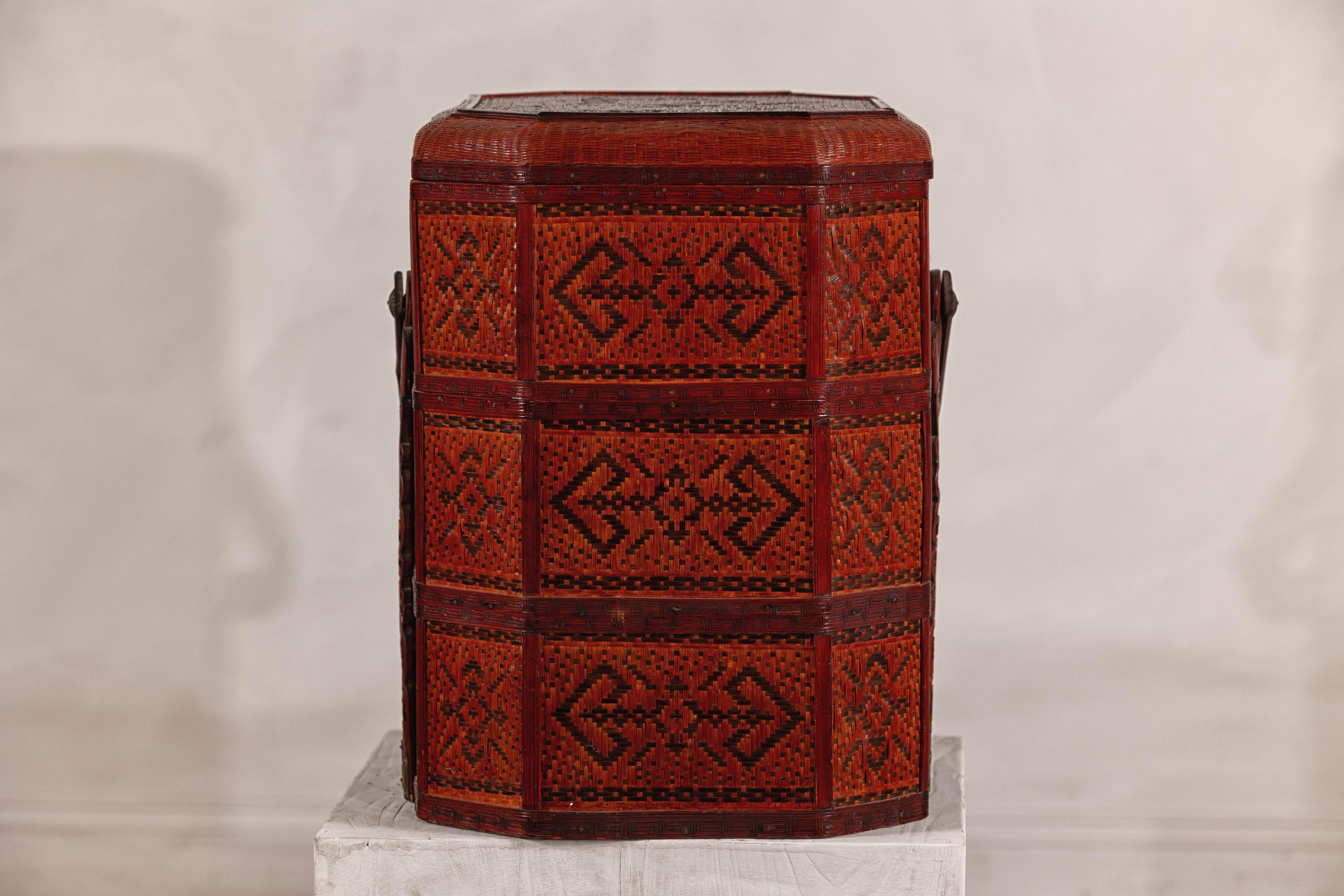 A hand-woven rattan Chinese picnic or wedding basket with carved bamboo handle. This vintage Chinese hand-woven rattan and bamboo tiered food carrier captures the essence of traditional craftsmanship with a striking brownish red lacquer finish. The