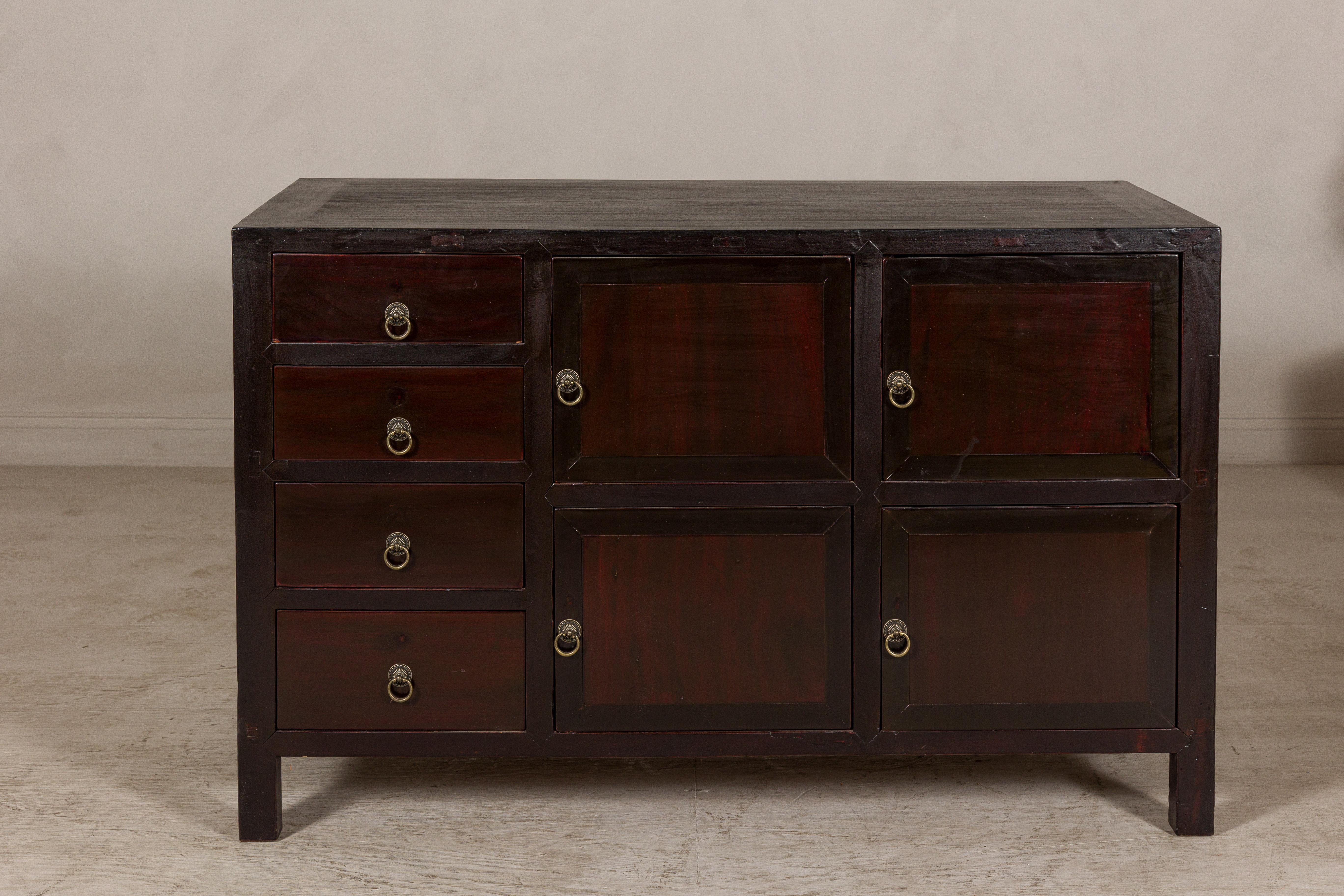 Con il suo ritmo geometrico e la profonda superficie laccata, questa credenza cinese vintage conferisce una struttura tranquilla agli interni, dal wabi-sabi sobrio al contemporaneo lucido. La facciata equilibrata offre quattro ante a pannello