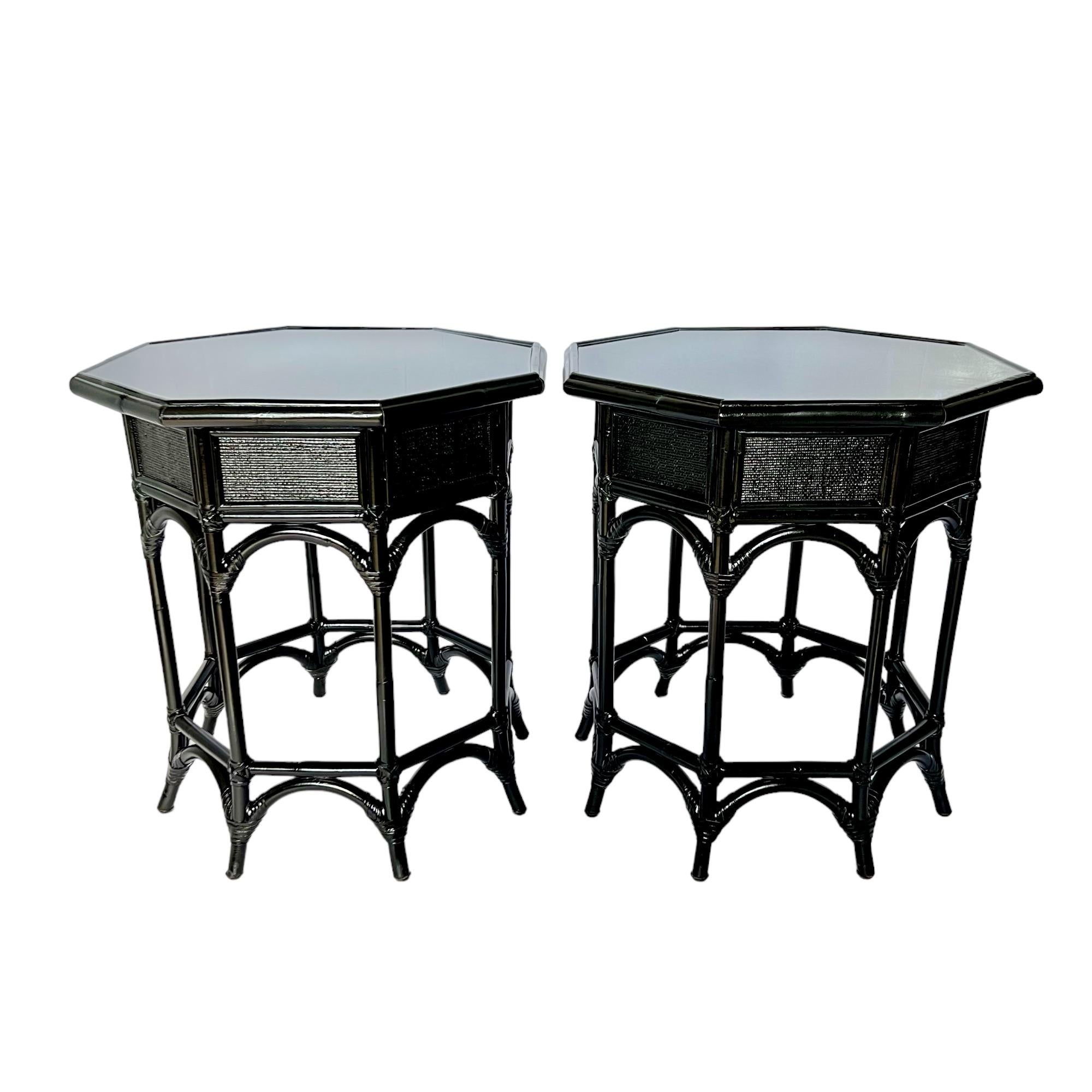 These vintage chinoiserie octagonal rattan tall accent tables have been custom refinished in semi-gloss black with inset epoxy resin tops. They feature woven apron panels, eight saber style out-turned legs connected by arched and straight