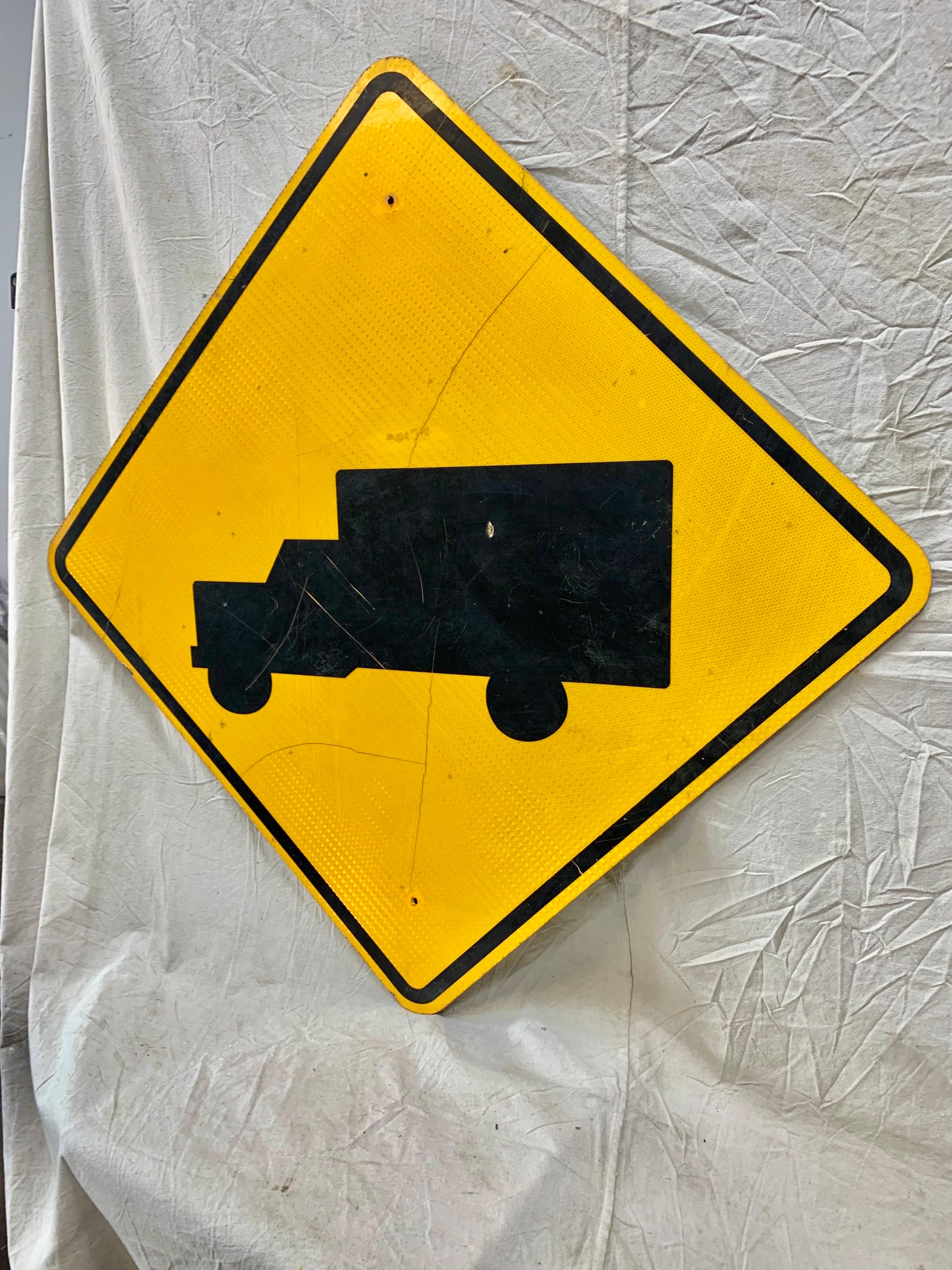 a yellow diamond shaped sign with a black picture of a truck on it means