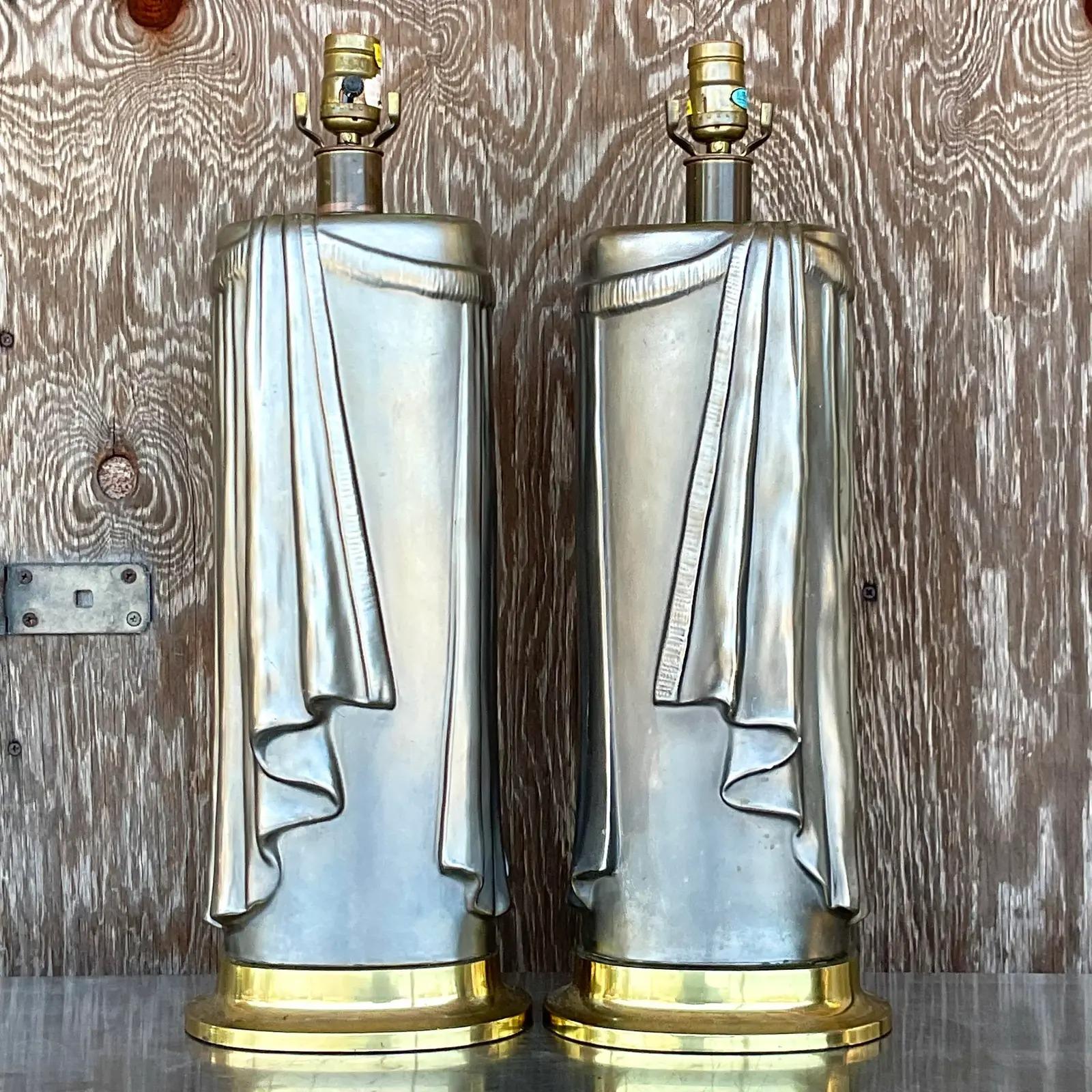 Fantastic pair of vintage Regency table lamps. Gorgeous swag design in a silvery matte glazed finish. Rest on brass plinths. Marked on the bottom. Acquired from a Palm Beach estate.