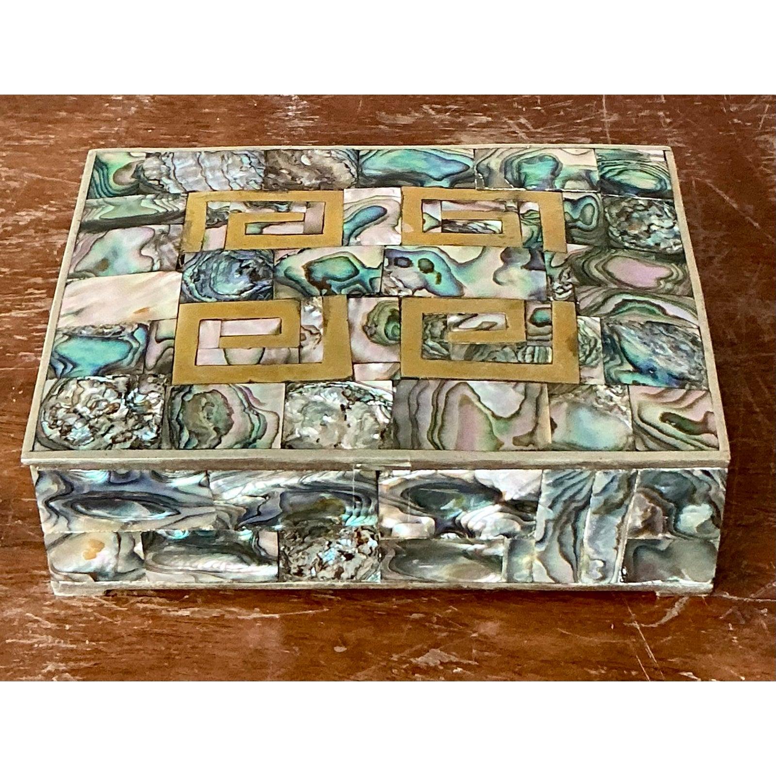 Scopri la squisita bellezza di questa scatola Regency d'epoca, una vera e propria testimonianza della sofisticata maestria dell'epoca. Questo splendido pezzo presenta un mosaico ipnotico di conchiglie abalone iridescenti, meticolosamente intarsiate