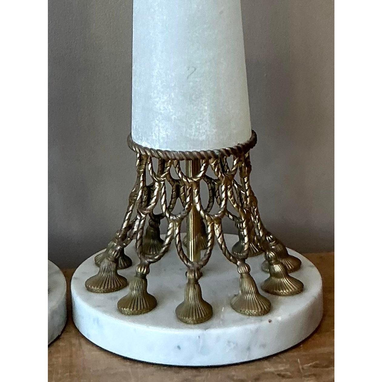 Irradia glamour atemporal con este sofisticado par de lámparas de mesa vintage Hollywood Regency. Una sorprendente mezcla de forma neoclásica y opulencia de mediados de siglo, cada lámpara presenta una esbelta columna blanca cónica -evocadora del