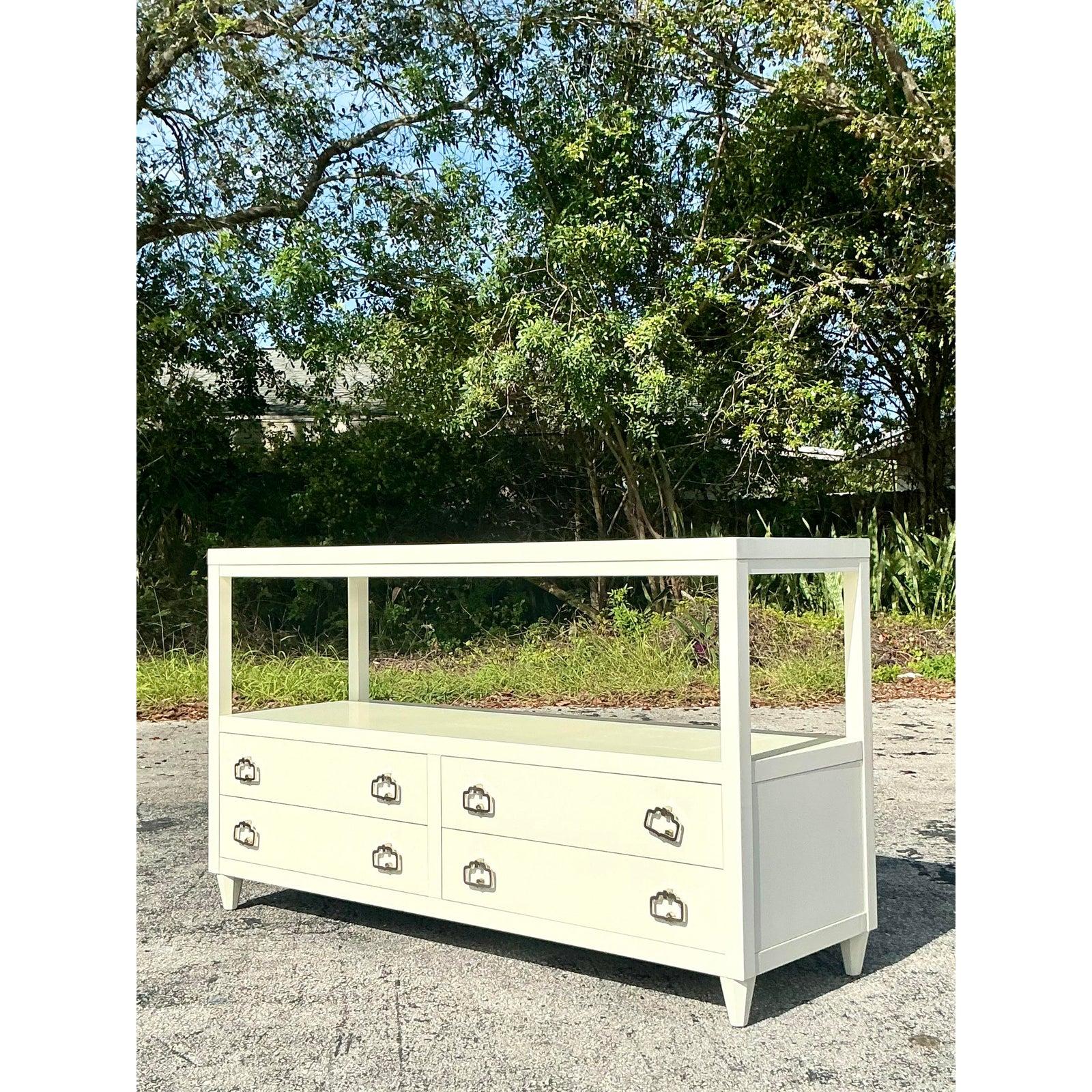 This exquisite Alexa Hampton for Hickory Chair credenza embodies timeless Regency elegance with its sleek lacquered finish and refined detailing. Featuring a spacious open shelf above four deep drawers, this piece offers both form and function,