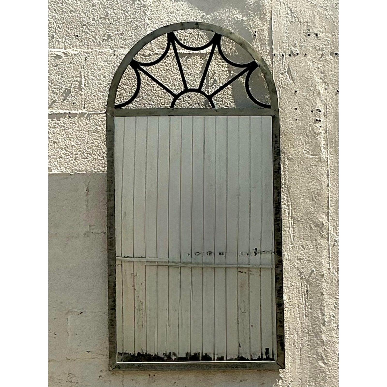 Eleganza scenografica per il tuo spazio con questo specchio ad arco in stile Regency vintage. L'irresistibile design è caratterizzato da una classica silhouette ad arco coronata da un intricato motivo a ragnatela o ragnatela metallica traforata, che