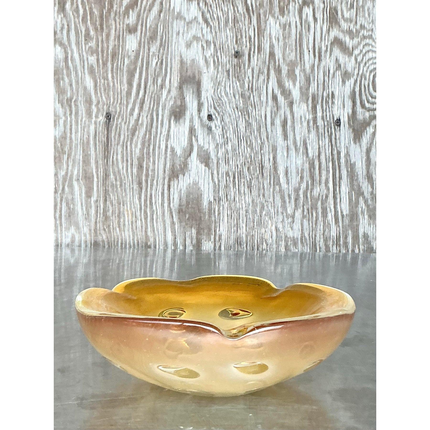 Ce superbe bol en verre d'art vintage respire l'élégance du milieu du siècle avec sa riche teinte ambrée et sa forme sculpturale, qui rappelle les modèles emblématiques en verre de Murano. La fabrication soufflée à la main met en valeur de délicates