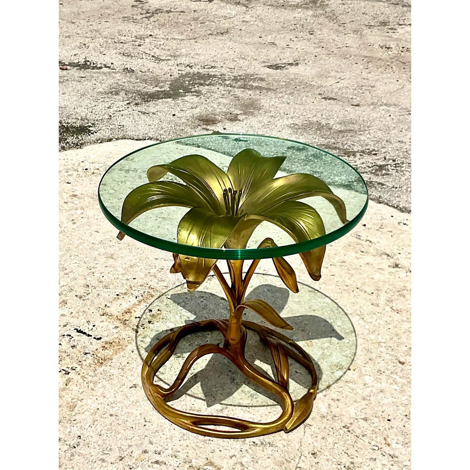 Fantastic vintage Regency side table. Beautiful gilt finish on the iconic large lily design. Thick glass top. Add a little drama to any space. Acquired from a Palm Beach estate.