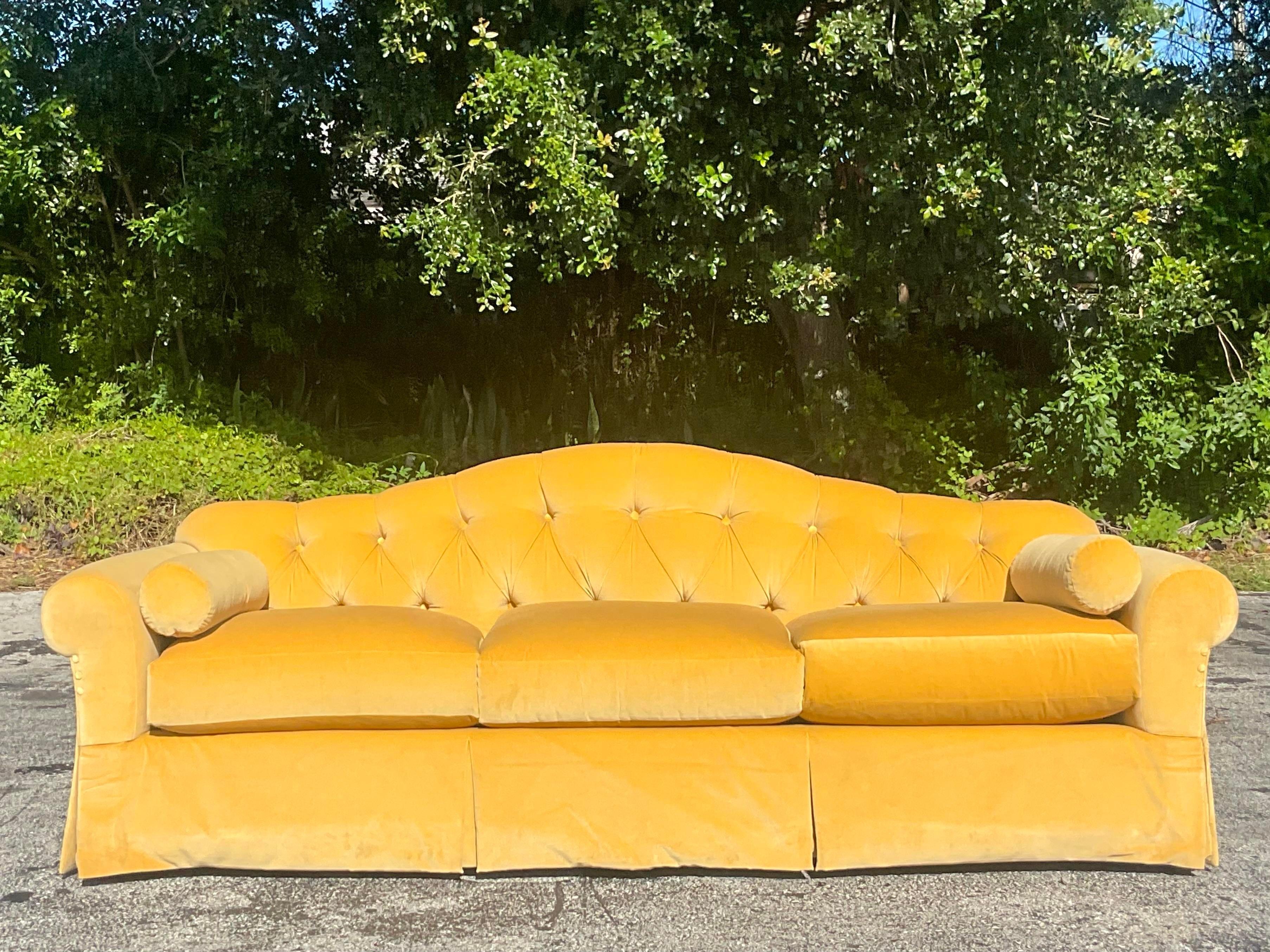 A stunning vintage Regency sofa. Made by the iconic Baker group and tagged below the seat. A brilliant yellow velvet and chic tufted detail. Acquired from a Palm a each estate.