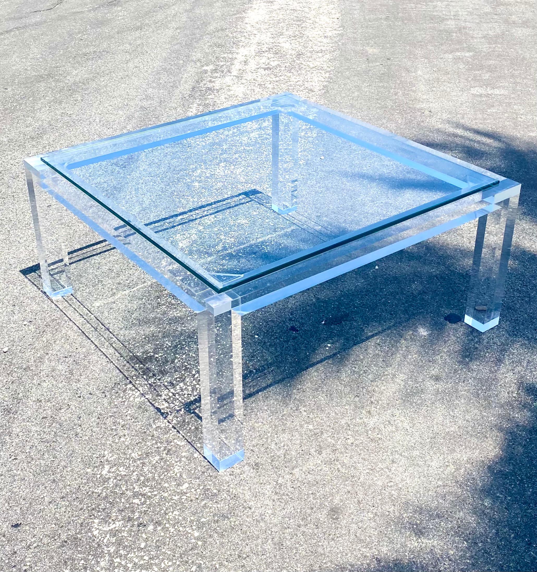 Stunning vintage Regency coffee table. Thick slab lucite in a contemporary square design. Glass tops rests on the surface. A really chic addition to any decor. Acquired from a Palm Beach estate.