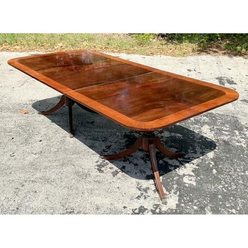 Experience the grandeur of bespoke dining with this magnificent Vintage Regency Birdseye Extendable Dining Table. A true embodiment of neoclassical elegance, this versatile table boasts a lustrous, dark wood surface, likely rich mahogany,